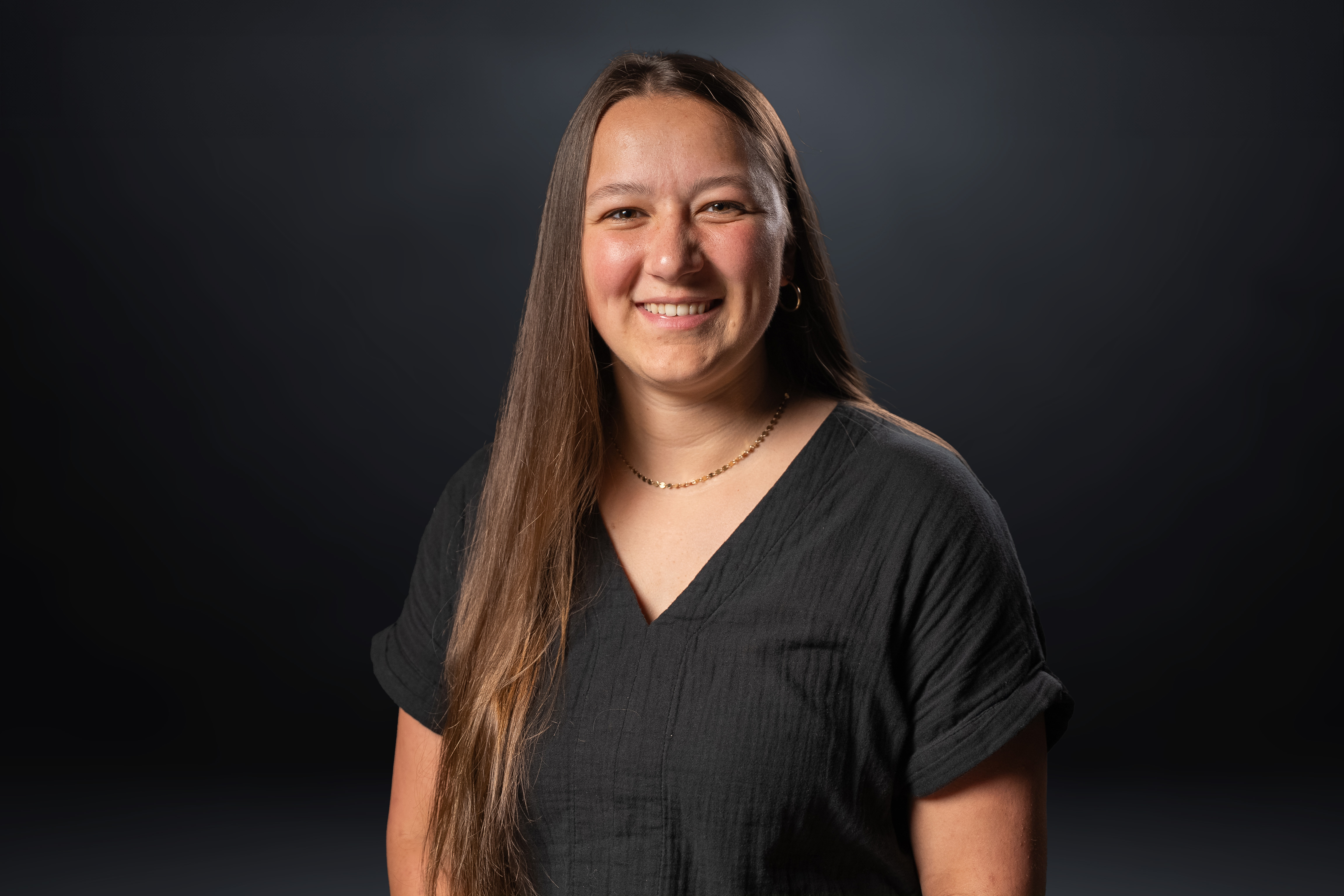 Chesser Media team headshot of a woman in black on gray backdrop.