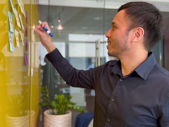 Veura CXO Julius Caesar Magsino applying sticky notes on a white board.
