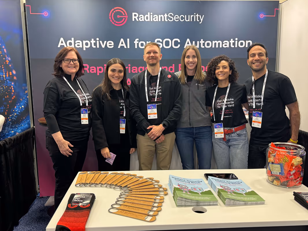 Radiant Security team standing together at their trade show booth wearing branded shirts and badges.