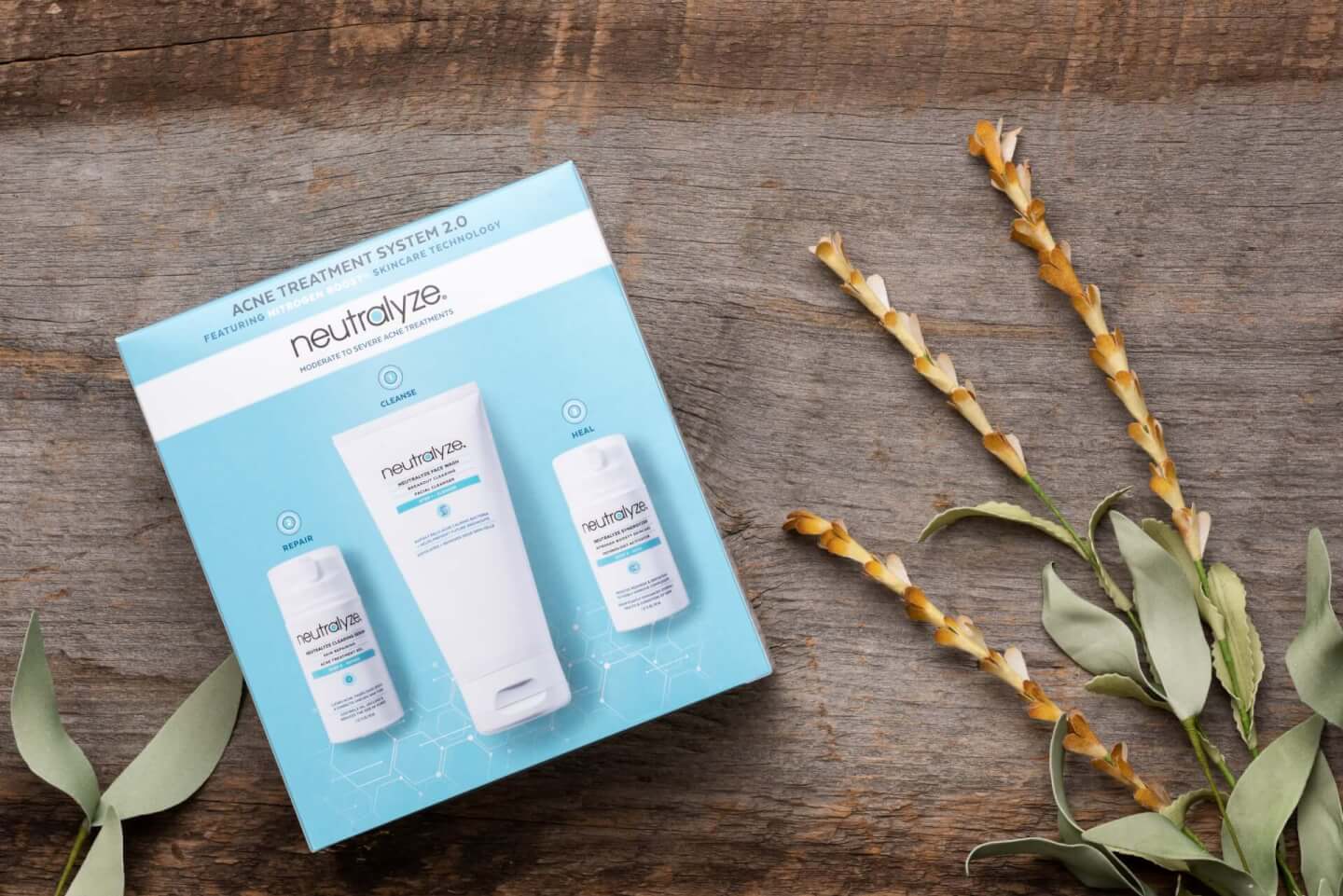 Three-step acne treatment kit box on a rustic wooden table with dried flowers