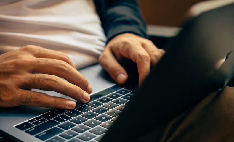 Close-up of hands typing on a laptop keyboard.