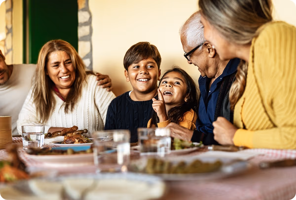 a latinx family talking and smiling around a dinner table.