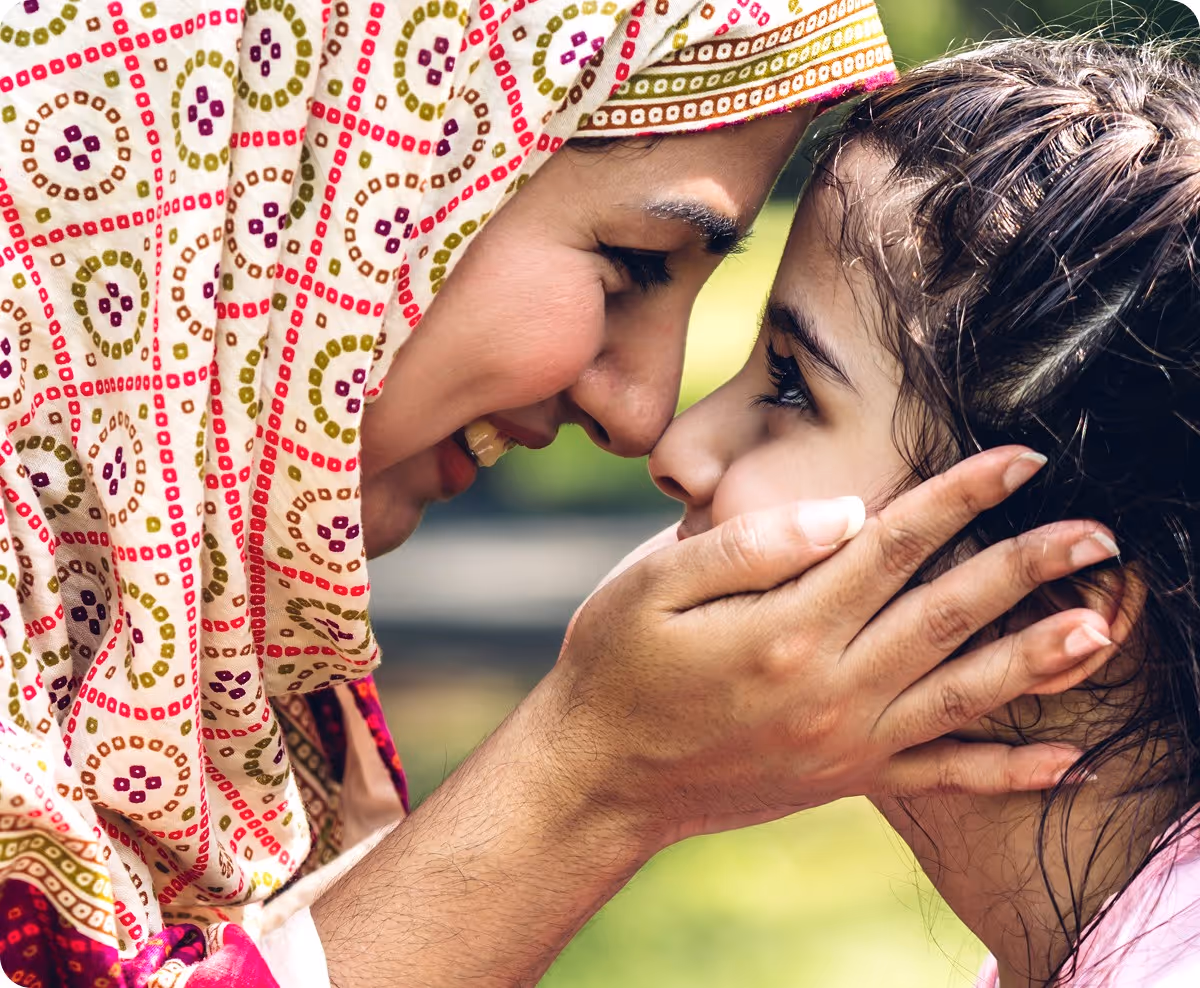 A muslim mother pushing her forehead to her child's forehead.