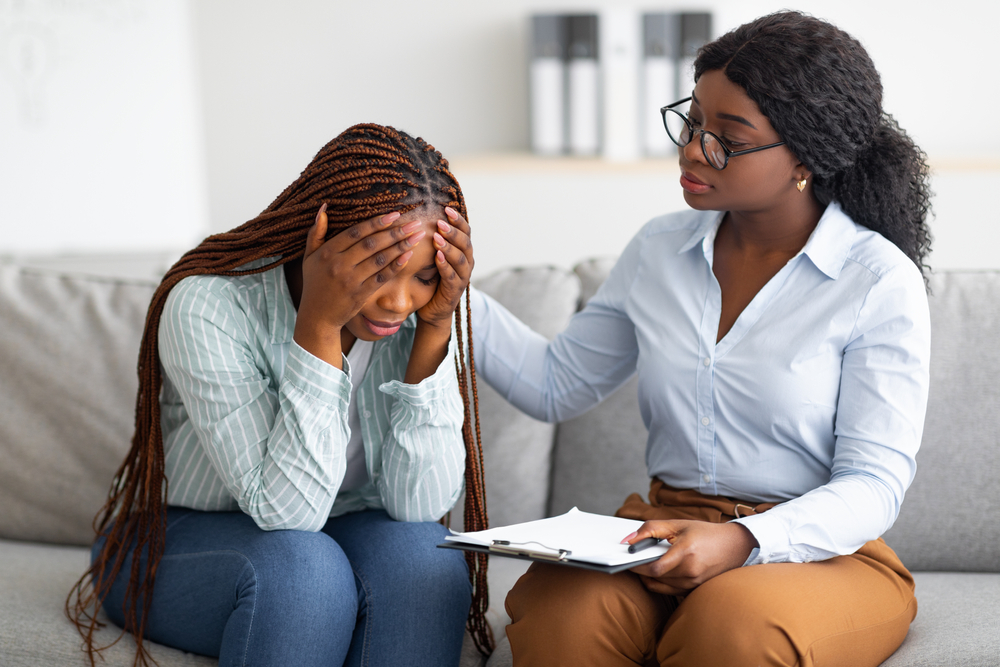 Upset lady with nervous breakdown consulting psychologist, having session with counselor at clinic. Professional psychotherapist comforting depressed female patient at office