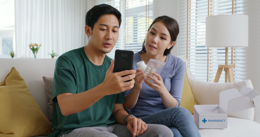 Young married asia people prepare pregnant plan checkup preconception consult at home sofa. Clinic app illness screen on online advice doctor remote exam telemedicine video call talk on tablet phone.