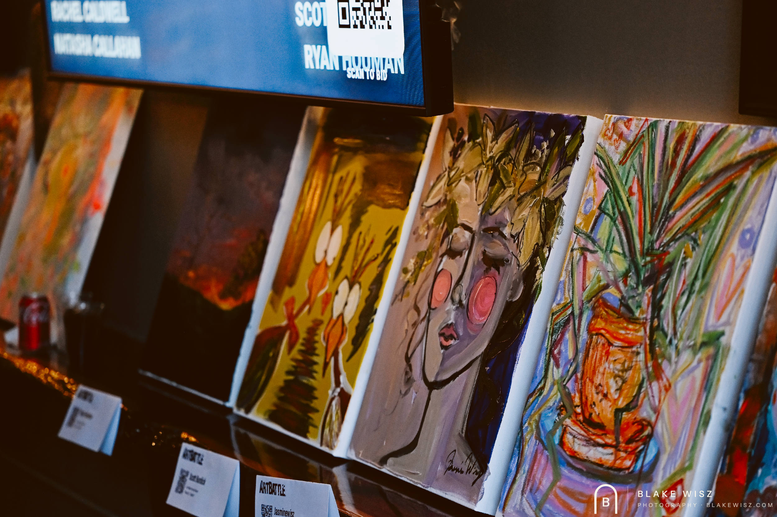Finished paintings lined up for auction at Art Battle Ormond Beach 2026