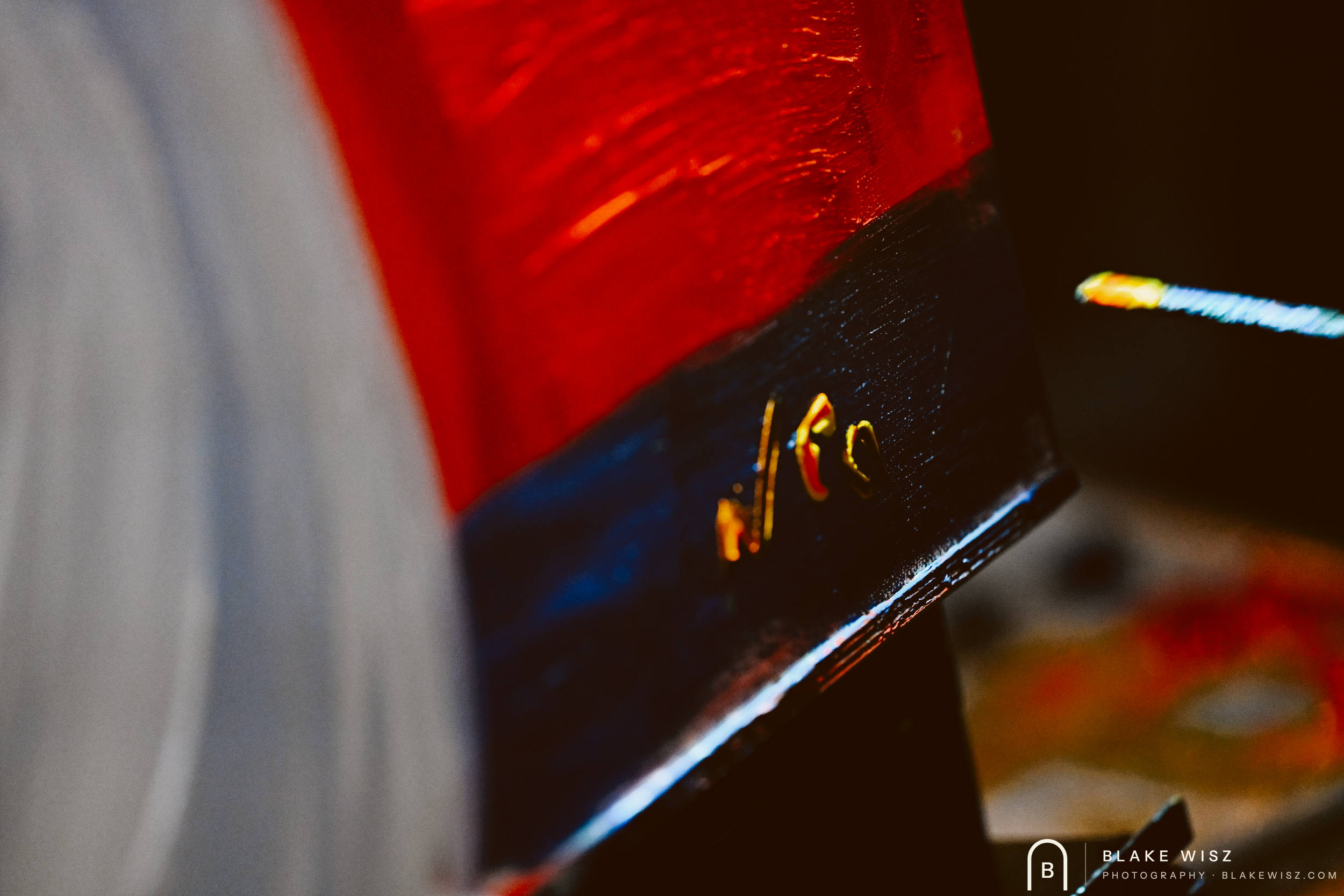 Close-up of a red and black painted canvas edge with the artist's signature, Art Battle Ormond Beach 2026