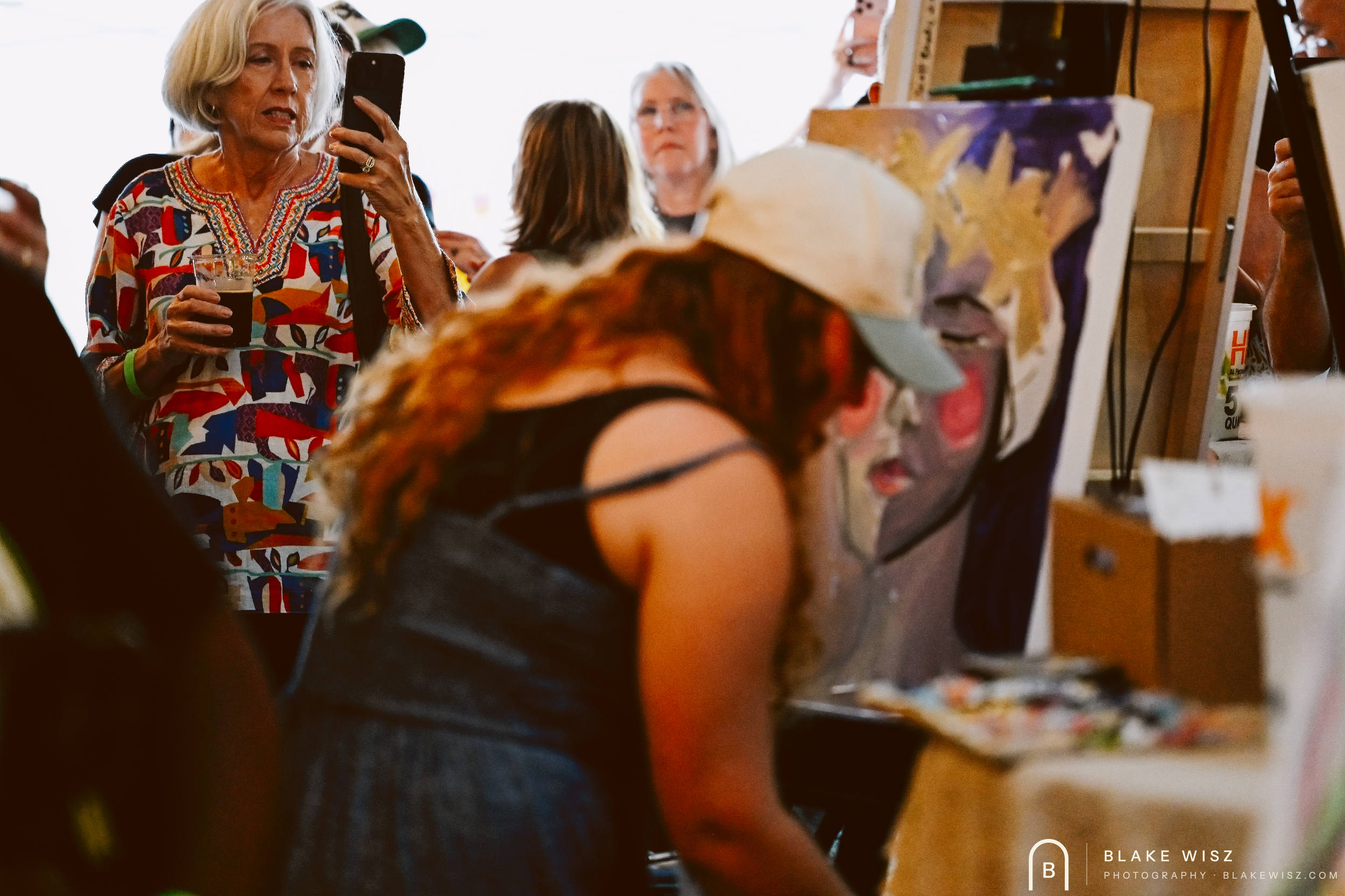 Spectators photographing Jasmine Wisz's canvas as she paints during her round