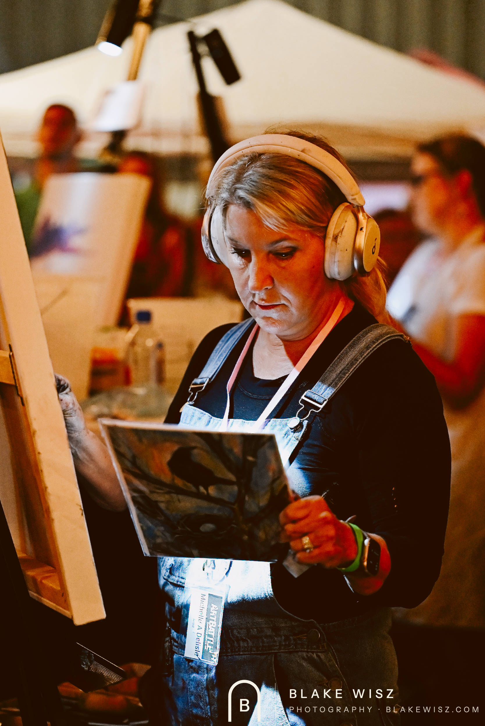 Michelle A Delisle checking her printed bird reference at the easel, Art Battle Ormond Beach