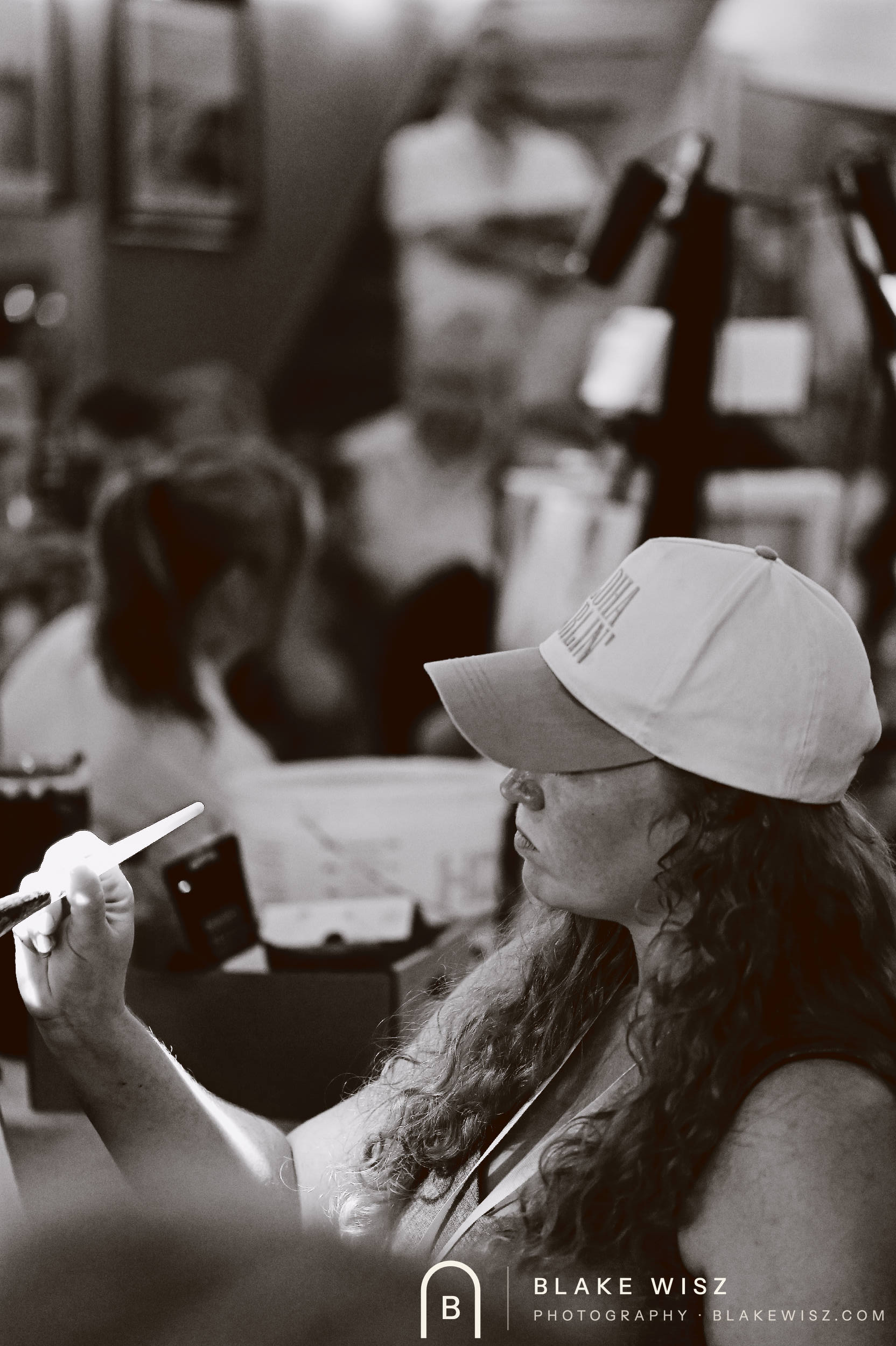 Black and white photo of an artist in a ball cap holding a brush between rounds