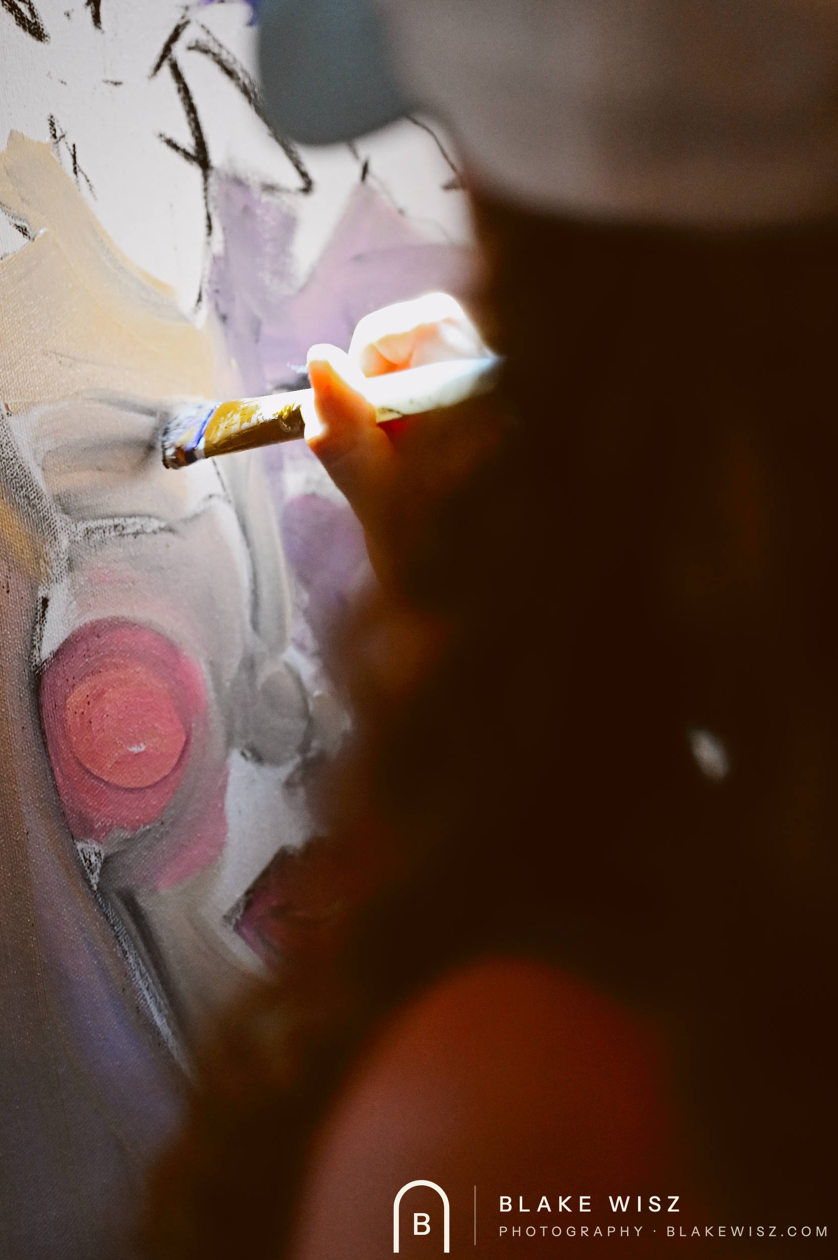 Artist's hand adding fine detail to a pale violet portrait at close range