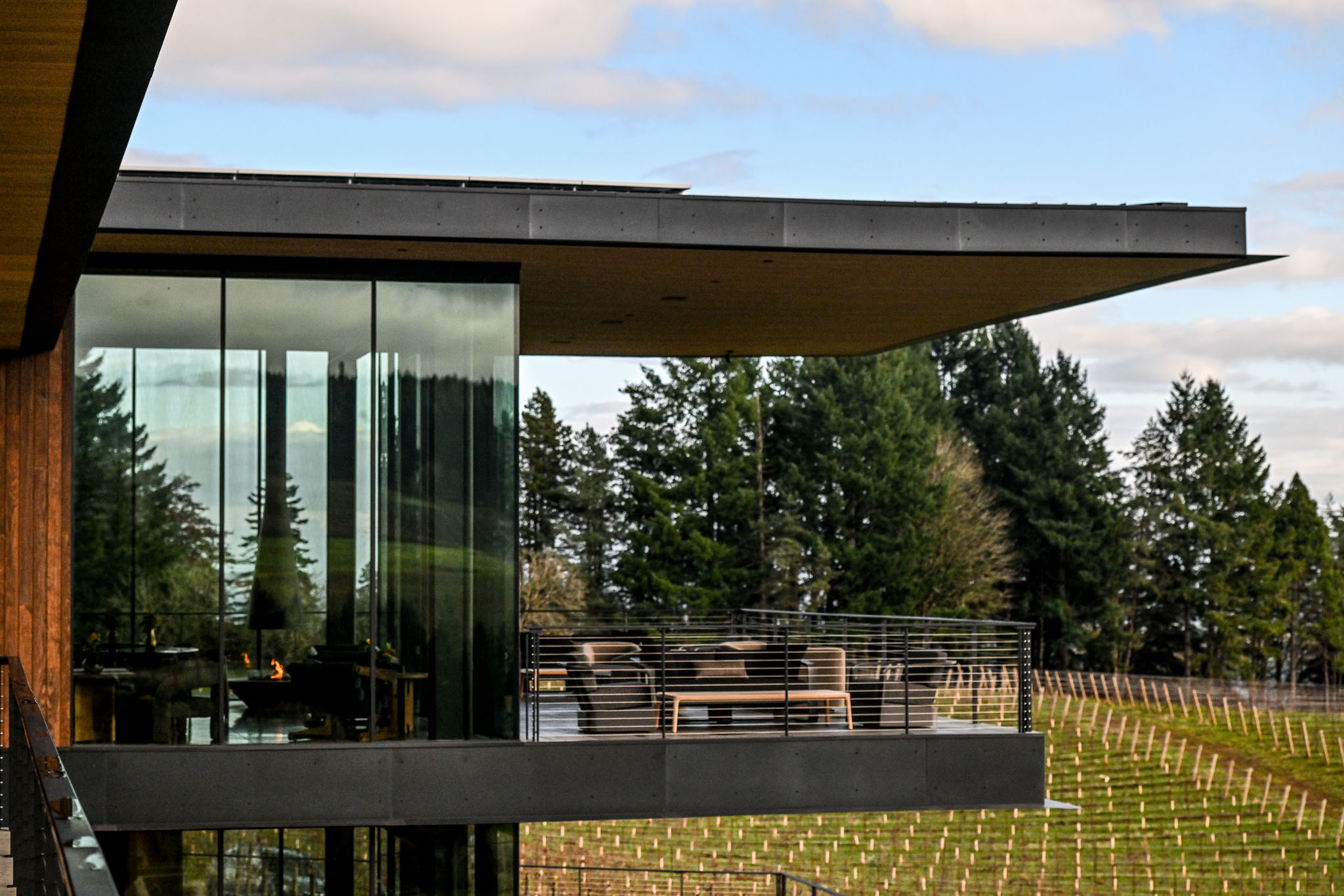 Cantilevered roofline and glass curtain wall over an outdoor deck at LucidWild Estate