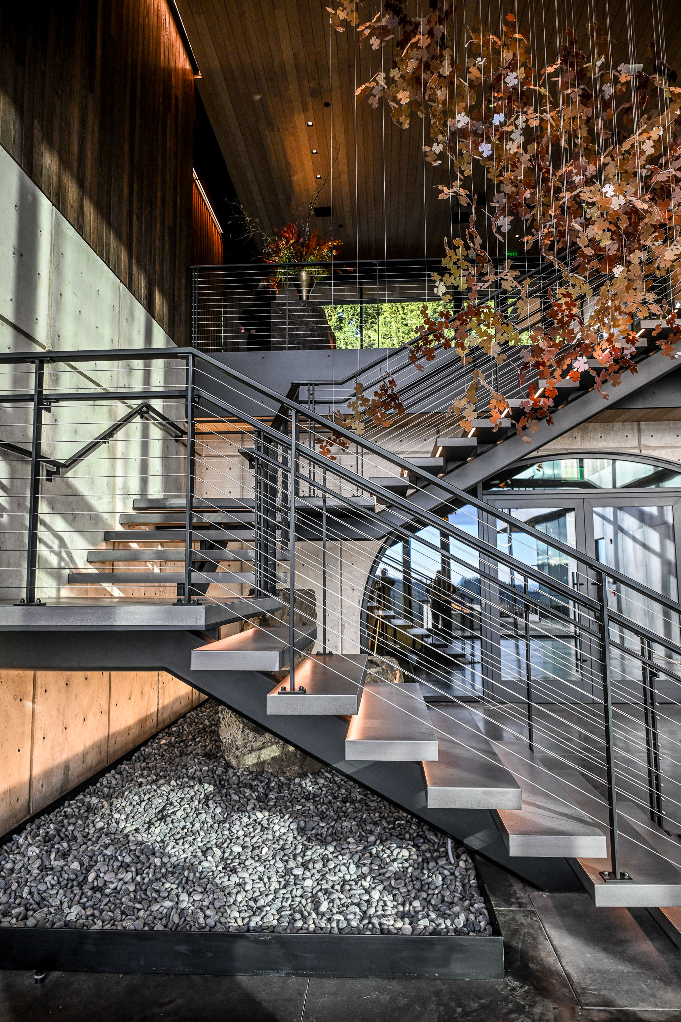 Floating steel and wood staircase with hanging autumn leaf art inside LucidWild Estate