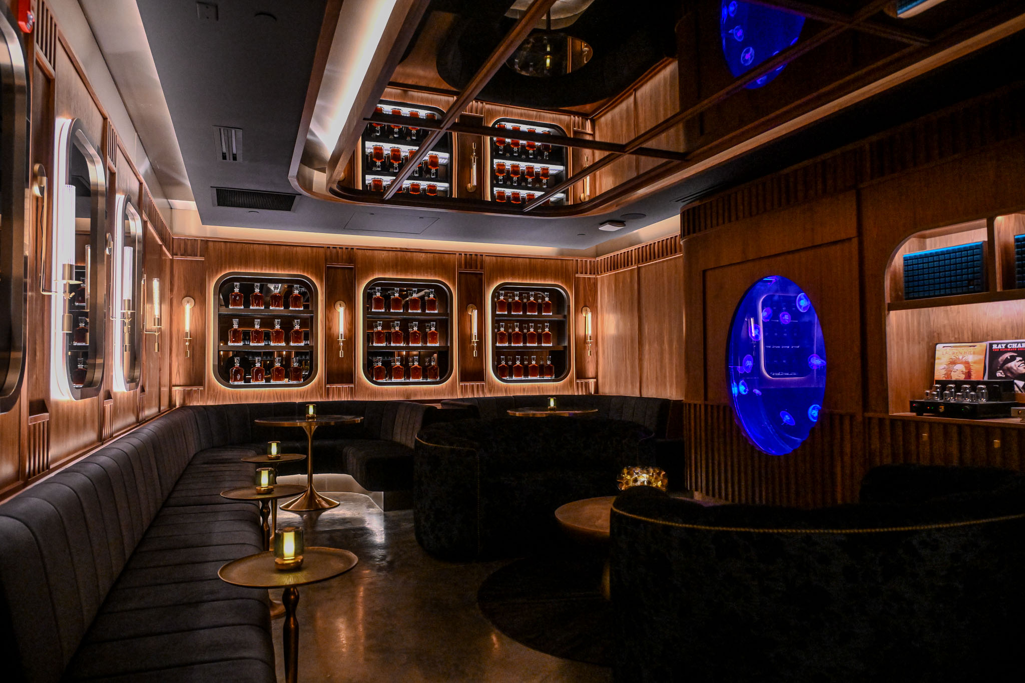 Wood paneled lounge at LucidWild Estate with a glowing blue portal and lit bottle cases