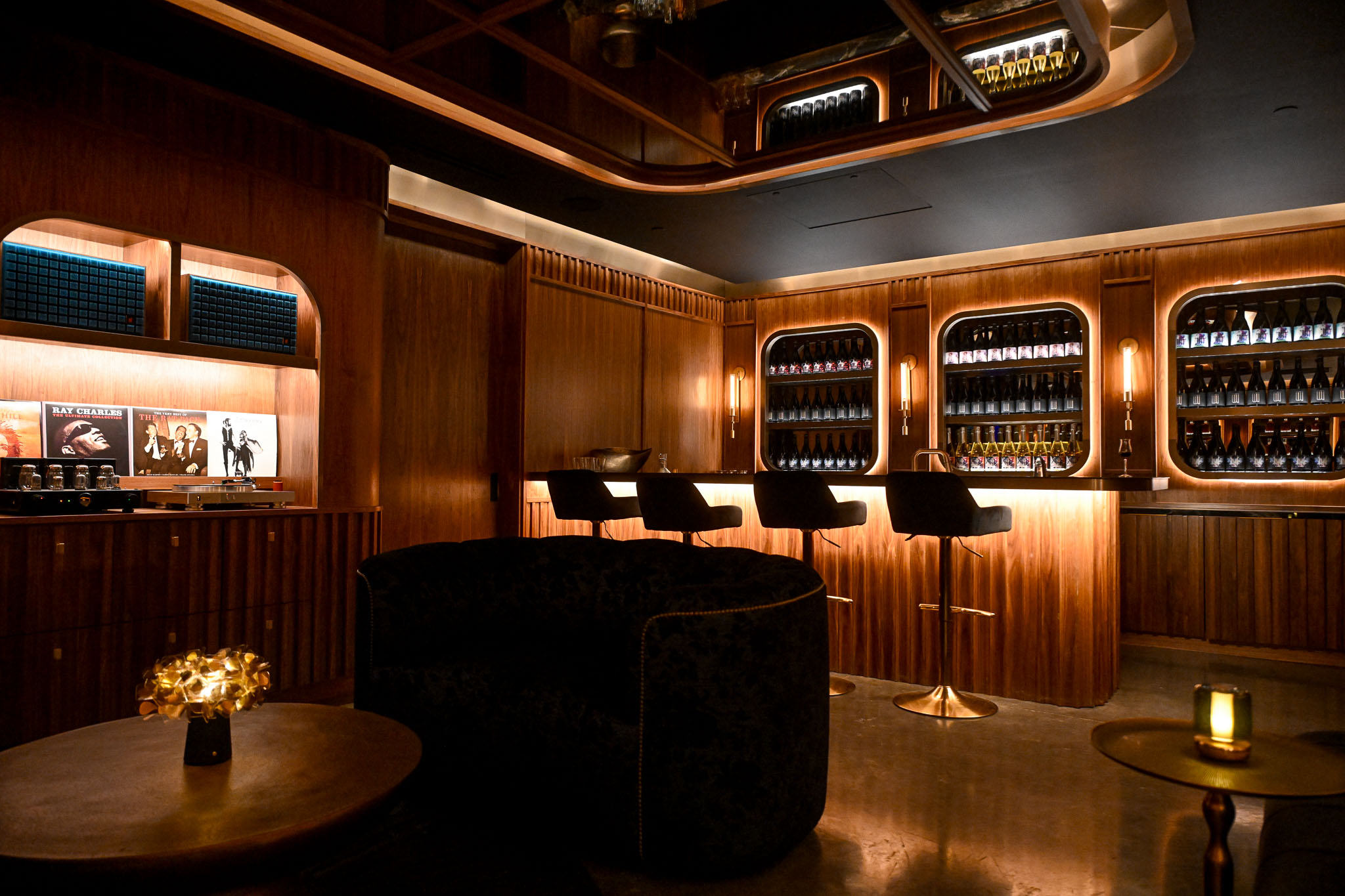 Curved bottle shop at LucidWild Estate with backlit shelving and a round bar of stools