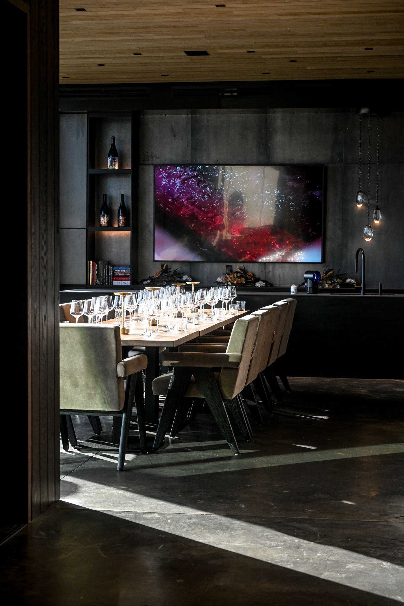 Wood ceilinged tasting room at LucidWild Estate with glasses set beneath a large screen