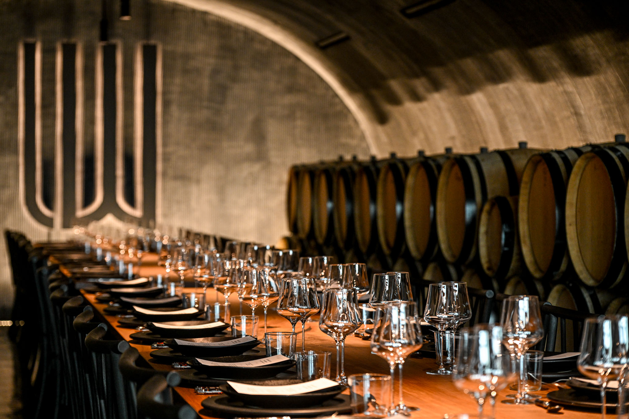 Wine glasses and place cards along the cave dining table beneath the illuminated W logo
