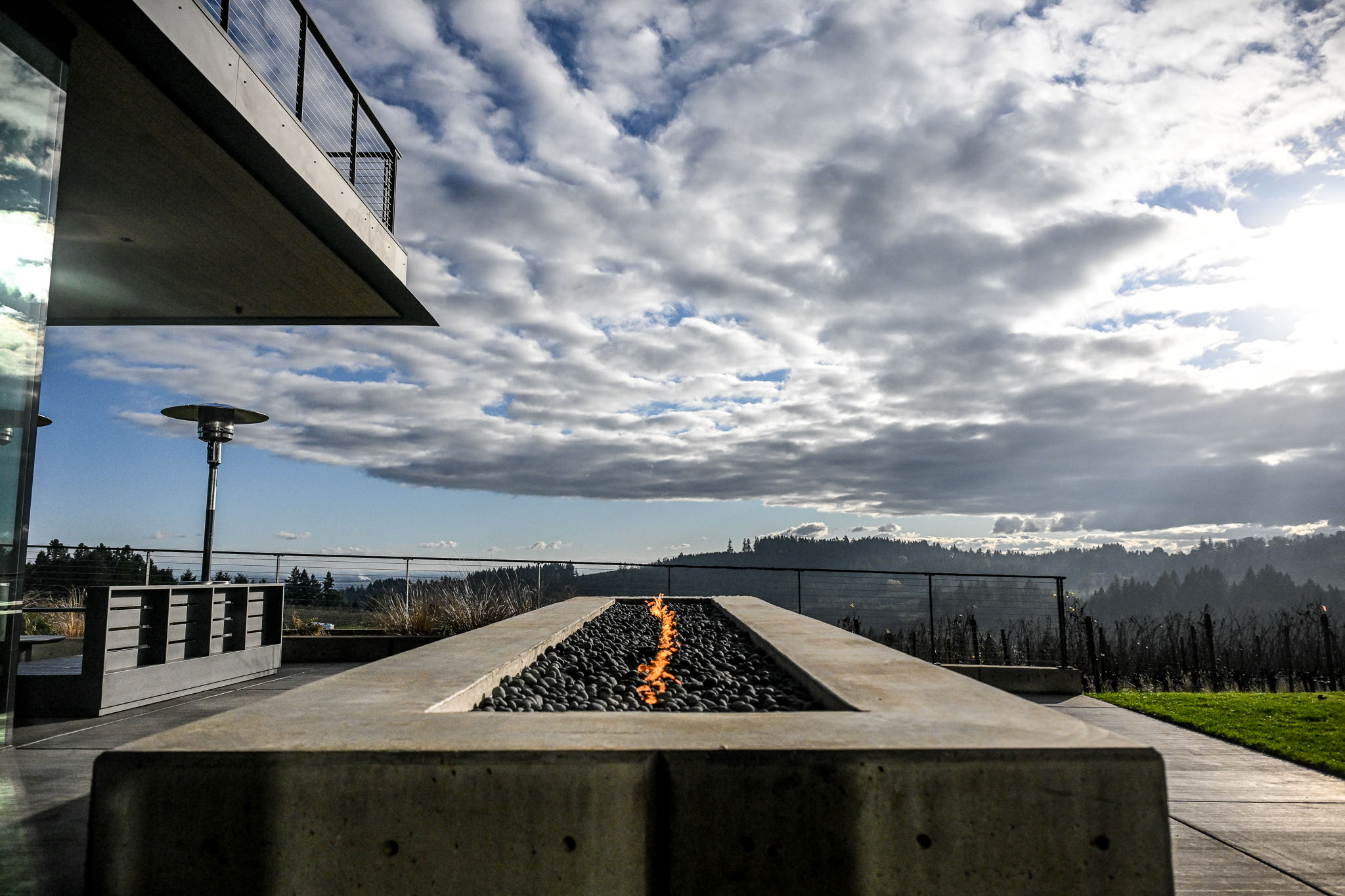 Concrete fire feature and terraced steps above a vineyard slope at LucidWild Estate