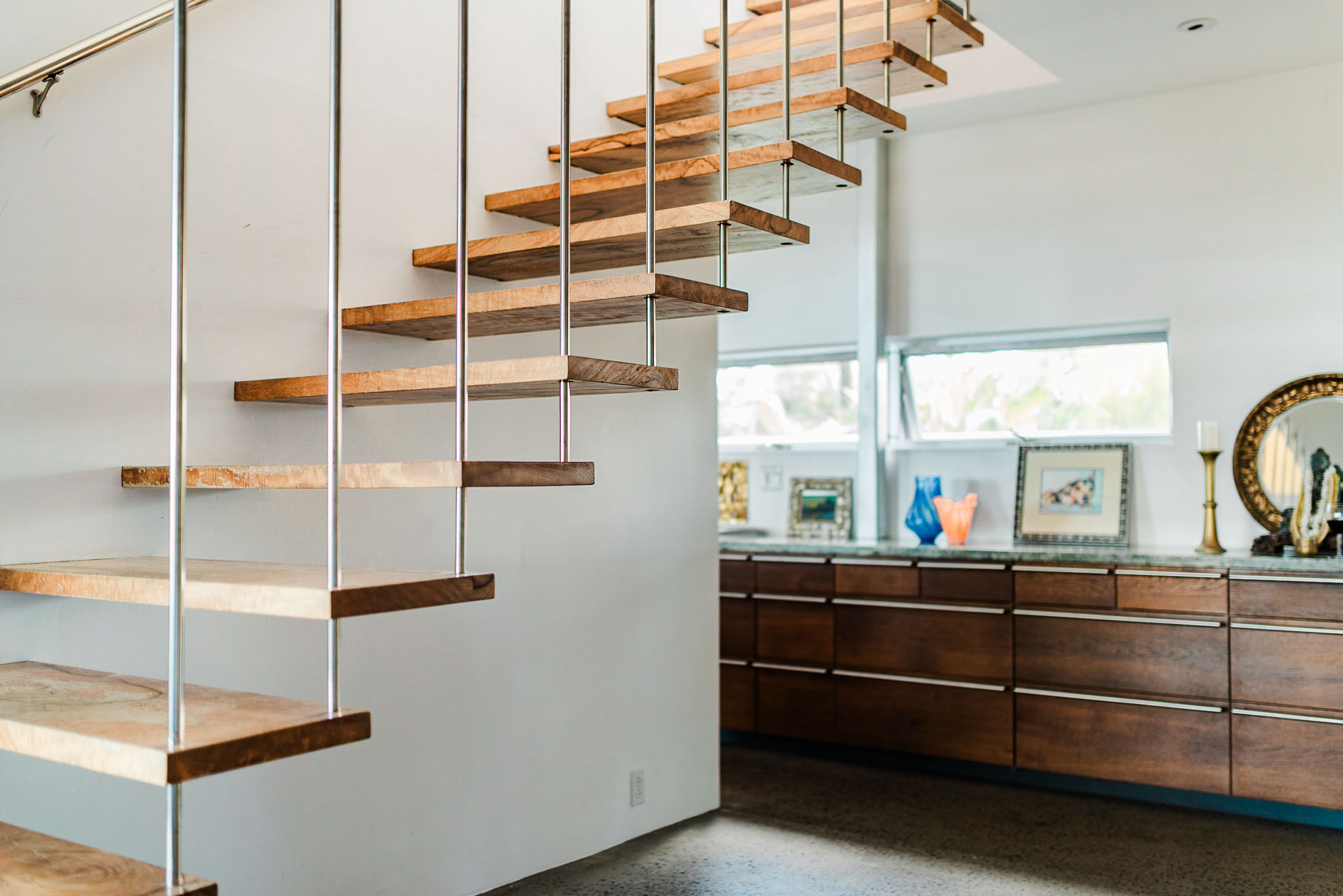 Cantilevered mango wood stair floating above a long credenza