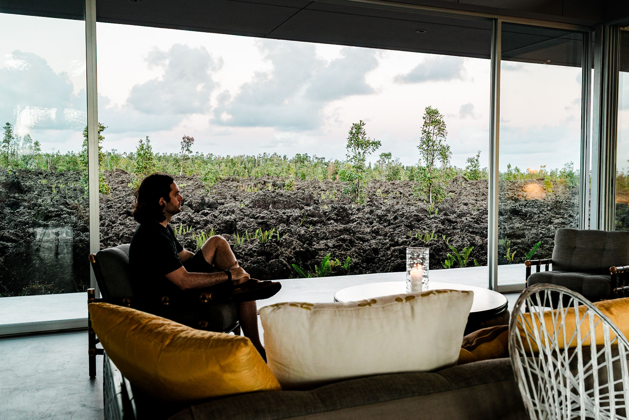 A guest in the glass living room looking out across the lava field