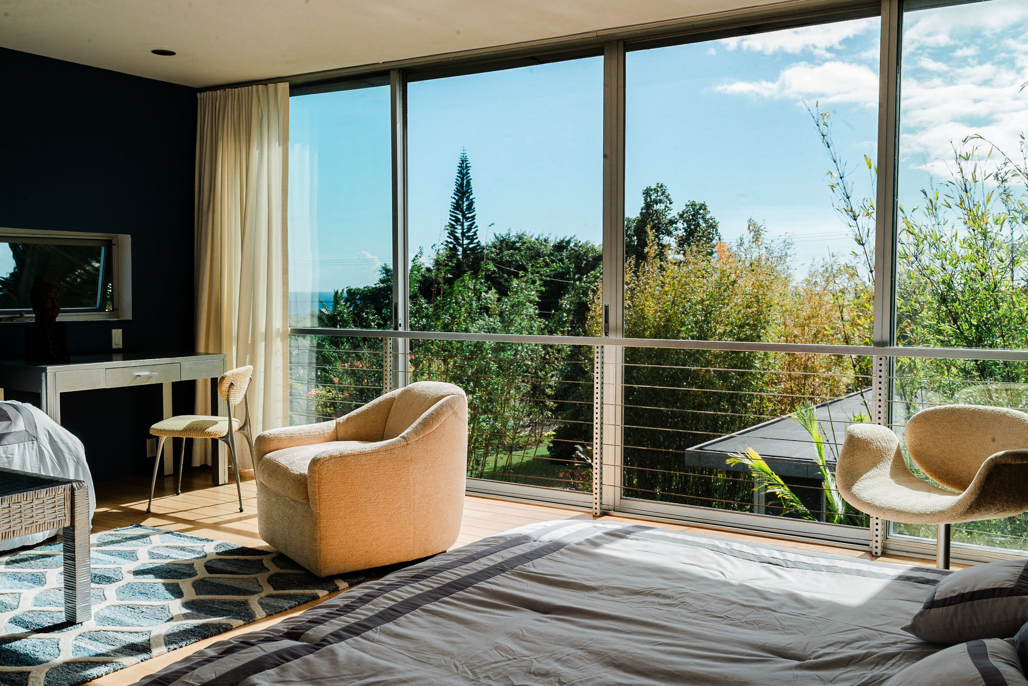 Blue bedroom with floor to ceiling glass opening onto a balcony