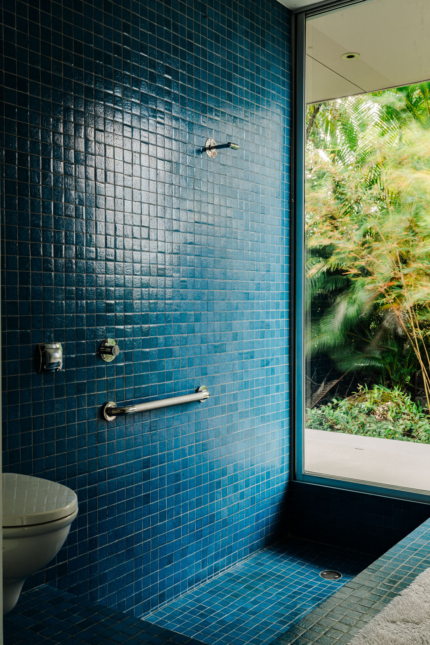 Blue tiled outdoor shower wall open to the garden