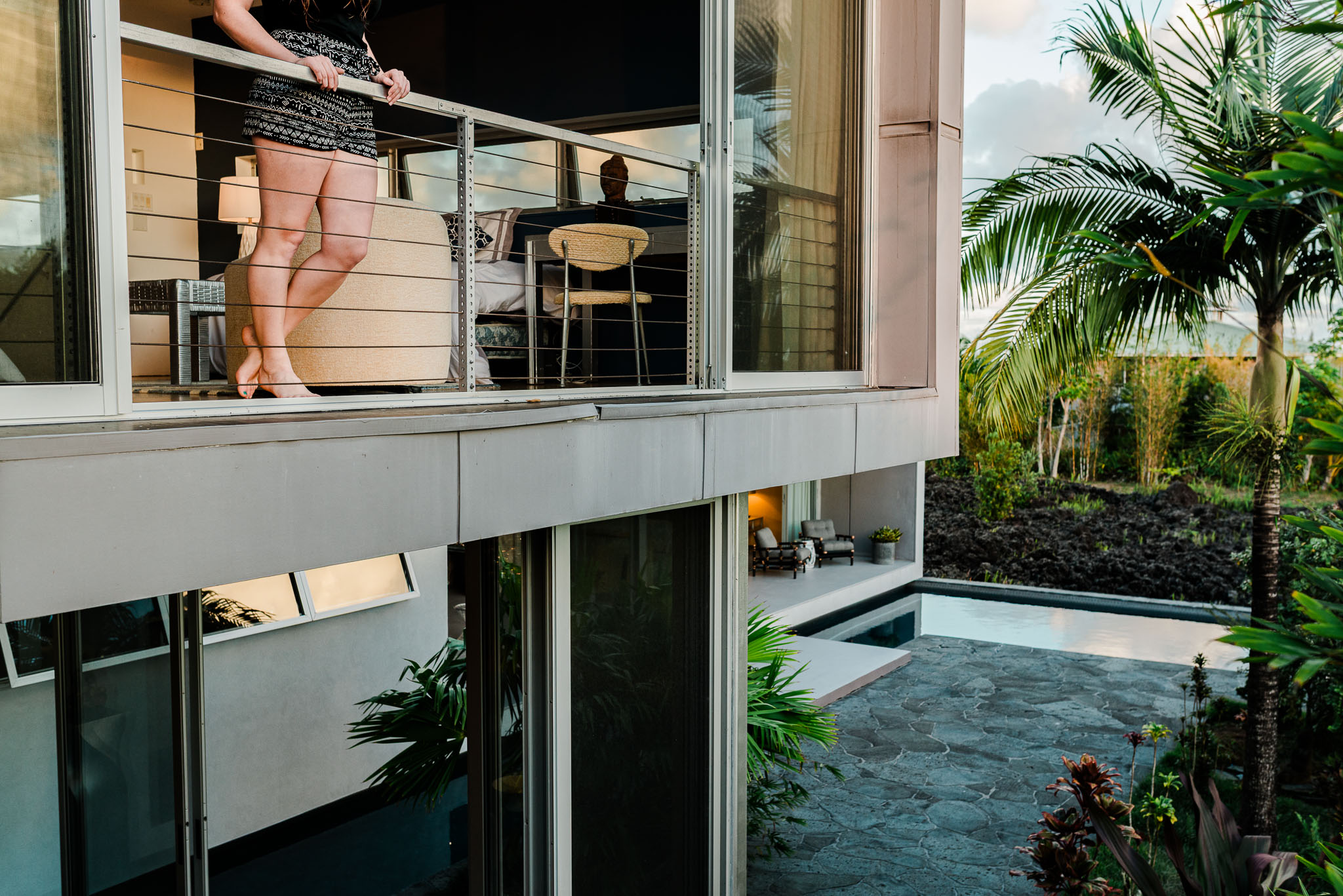 The two storey glass elevation of the house above the pool and palms