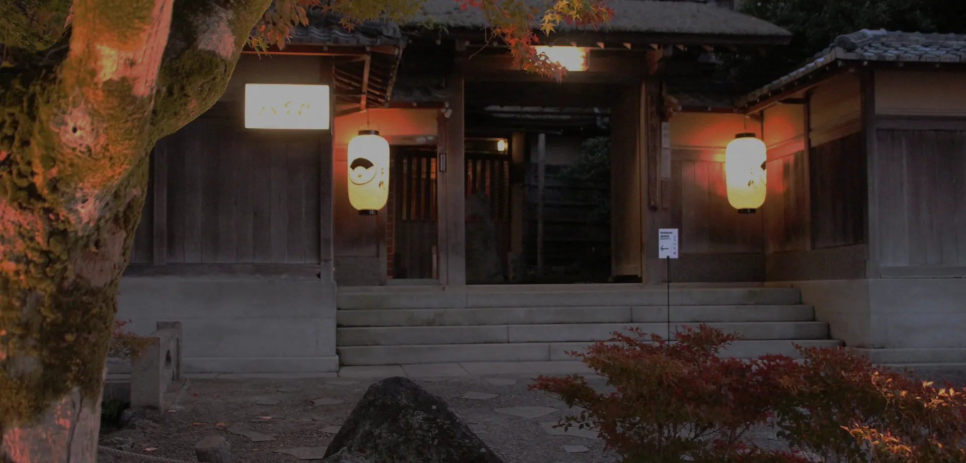 大分・別府の自然に囲まれた温泉旅館の玄関外観。夕暮れに灯籠が灯る落ち着いた雰囲気の入り口