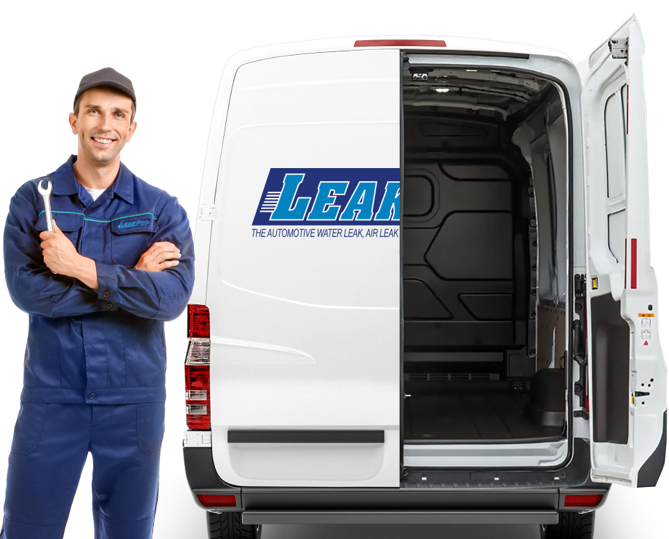 A man in blue overalls smiling and holding a wrench in front of an open van