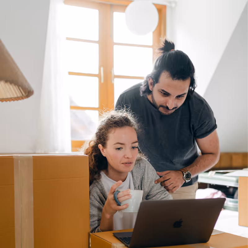 young couple using laptop in house with boxes