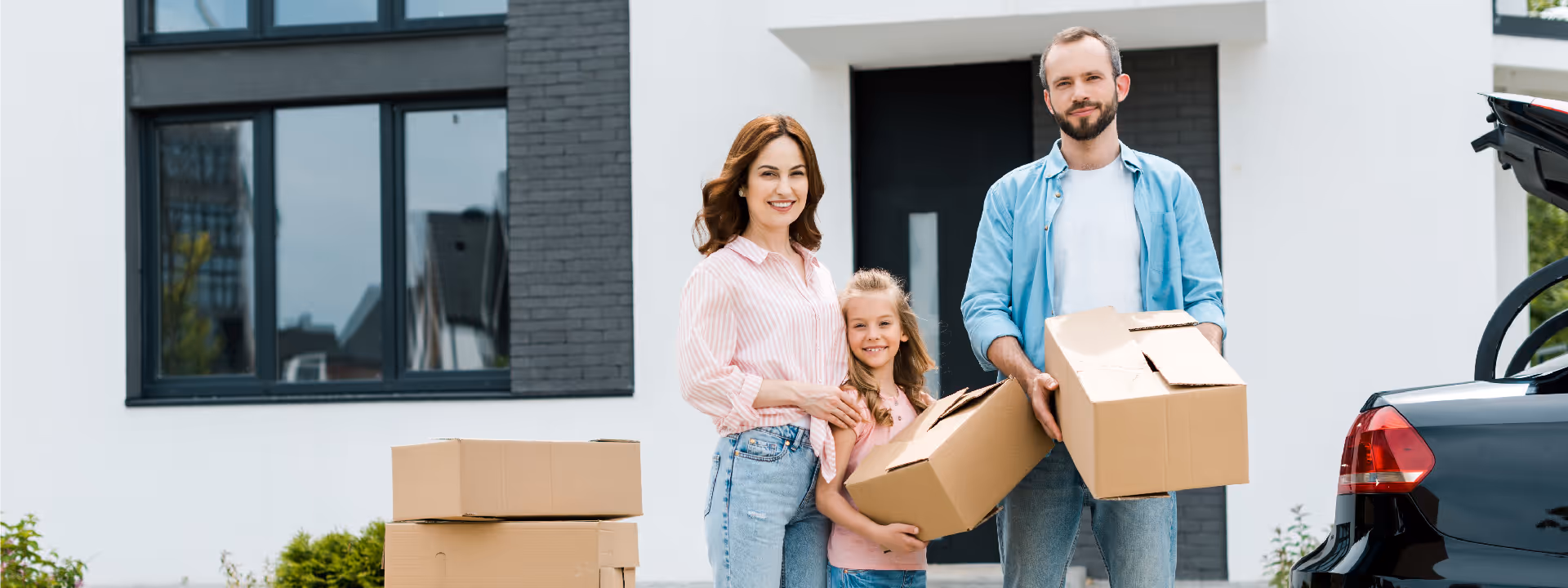 young couple standing outside house with boxes