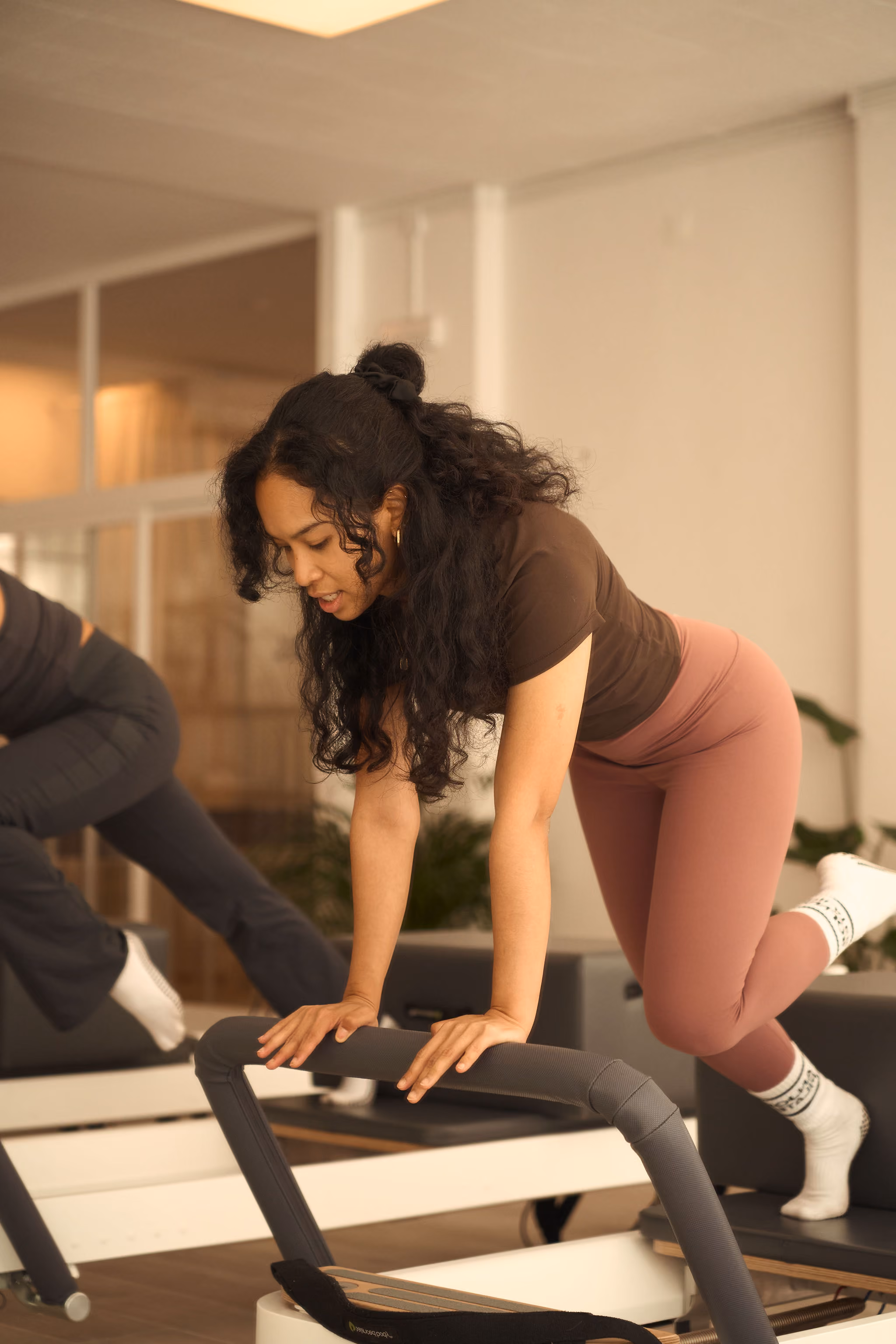 Person in black sportswear performing a side plank exercise on a Pilates reformer machine.