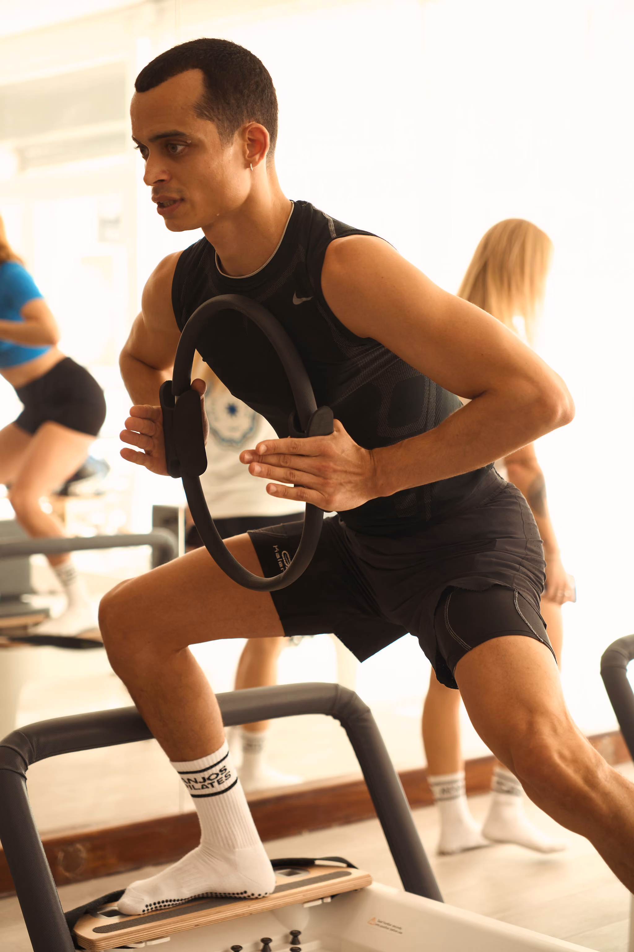 Person in beige leggings and white socks doing a Pilates exercise on a reformer machine.