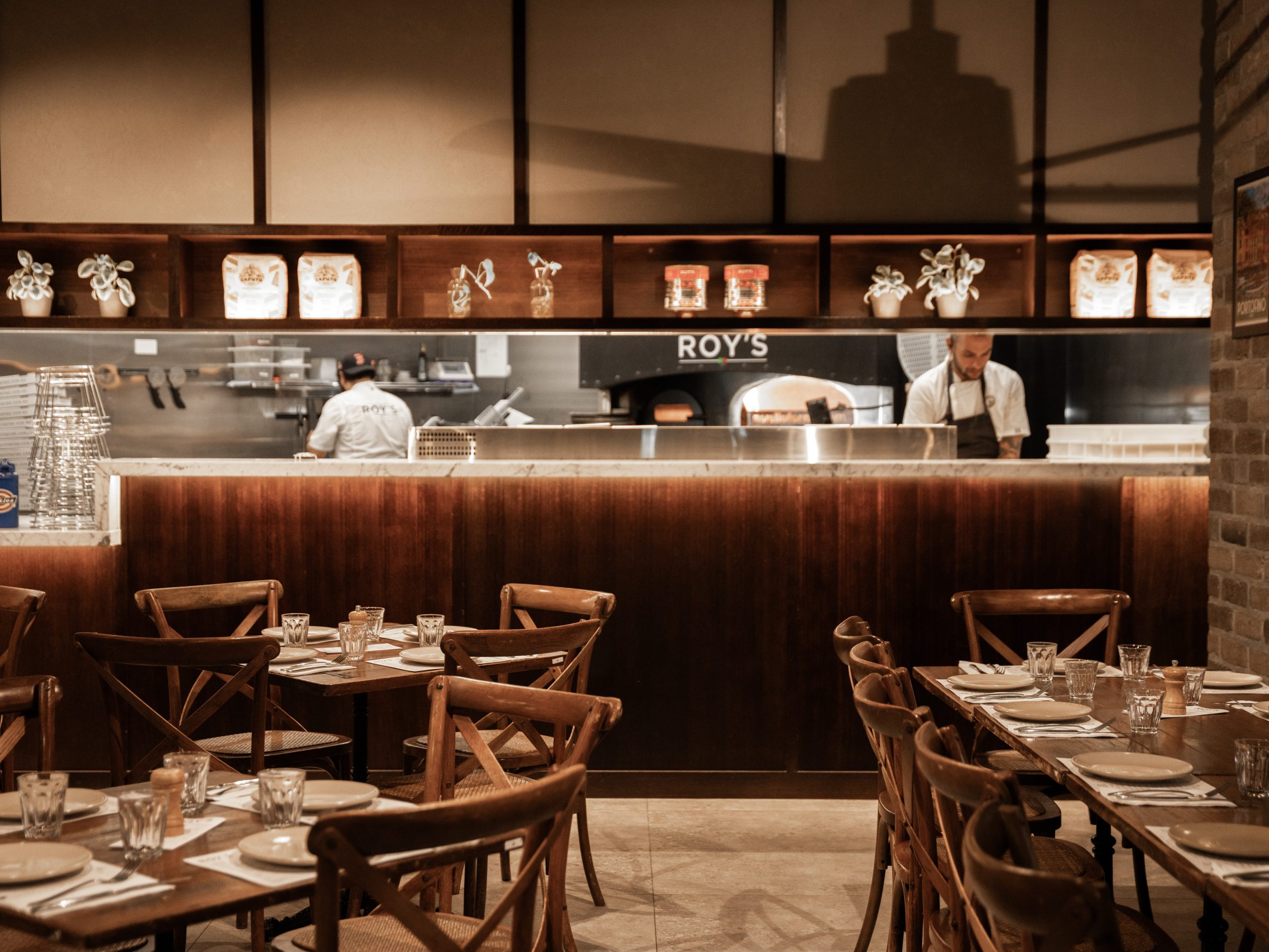 A restaurant kitchen with chefs preparing food behind a wooden counter.