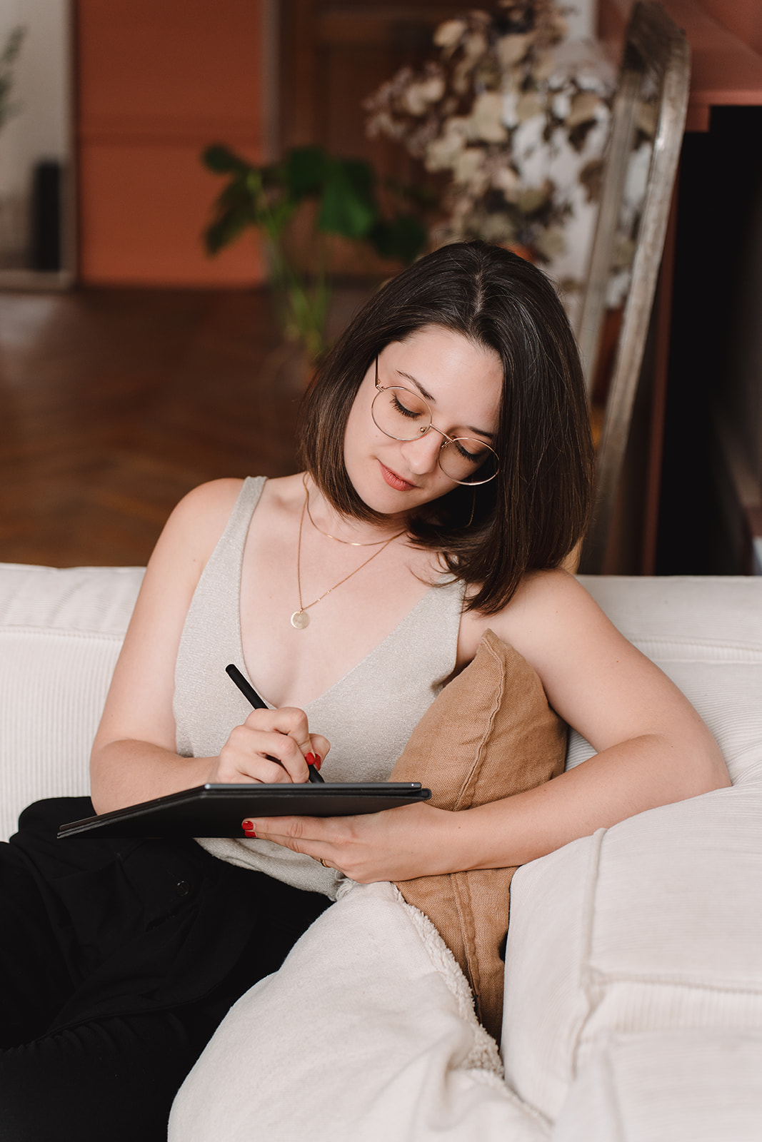 Sur un canapé crème, Line écrit sur sa reMarkable, un carnet digital, concentrée.