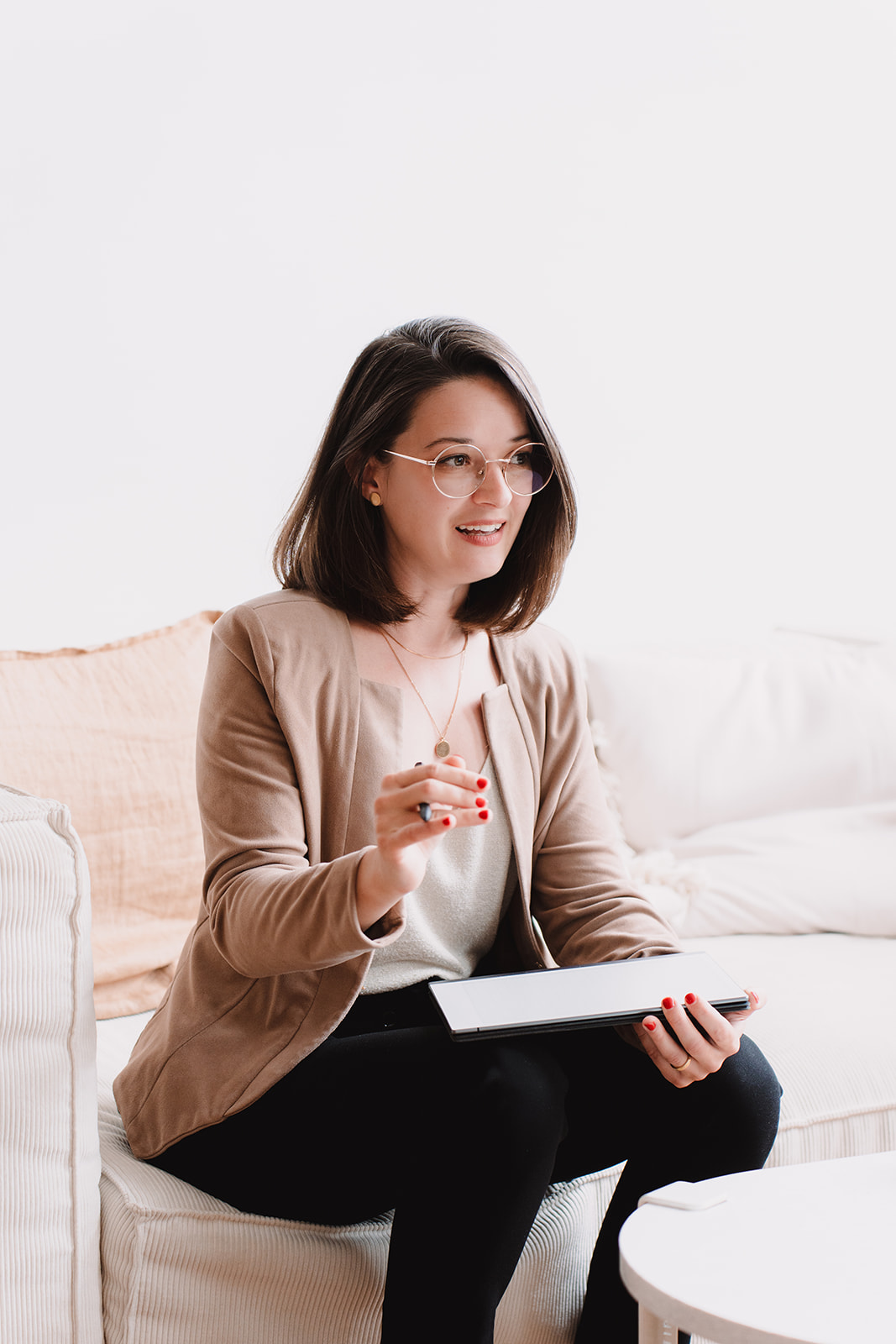 Line, entrepreneure en consulting. Assise sur un canapé, elle parle avec les mains un carnet digital dans une main