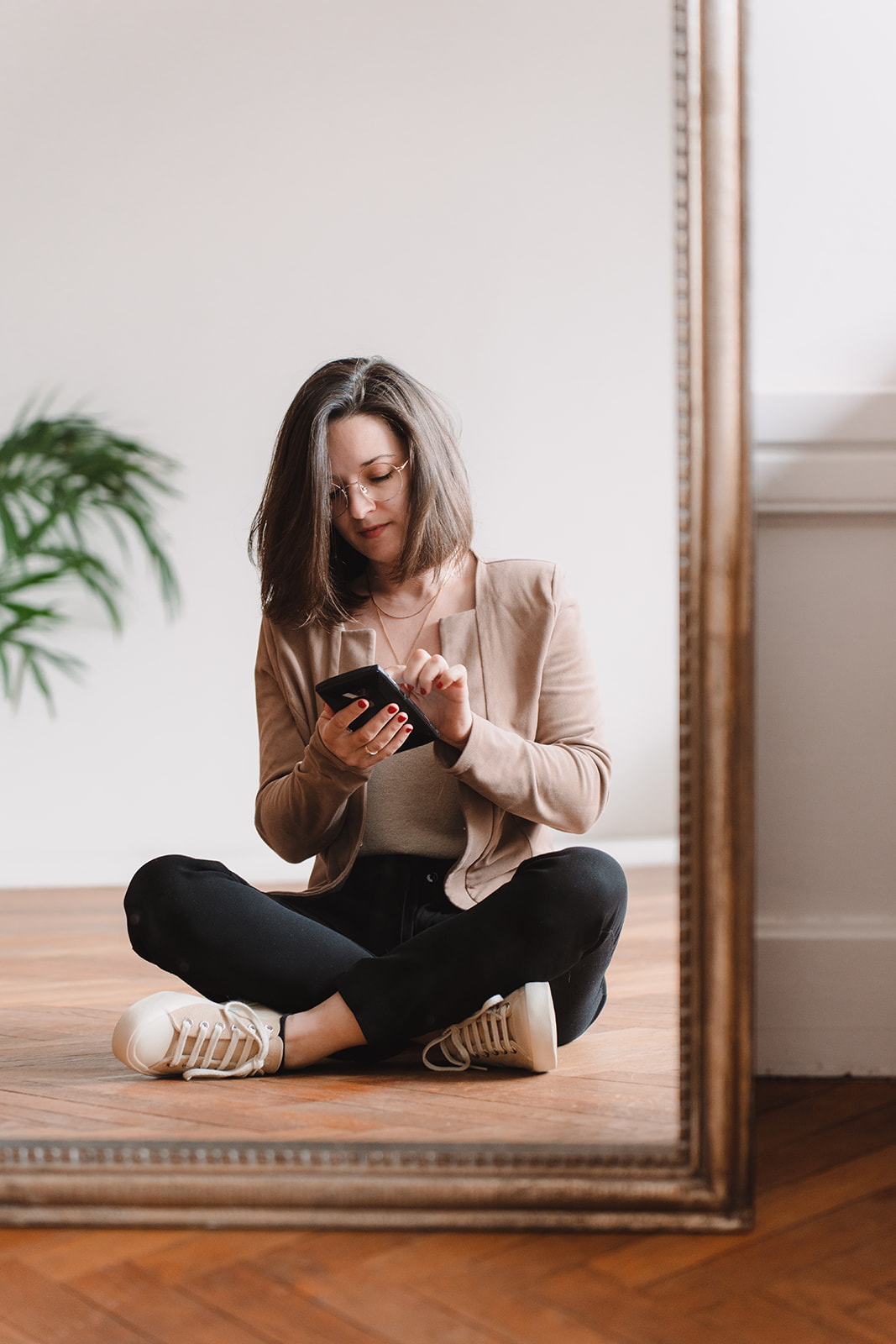 Line, jeune femme entrepreneure, est assise en tailleur. Le reflet du miroir face à elle la montre les yeux baissés sur son téléphone. Elle y écrit un texte.