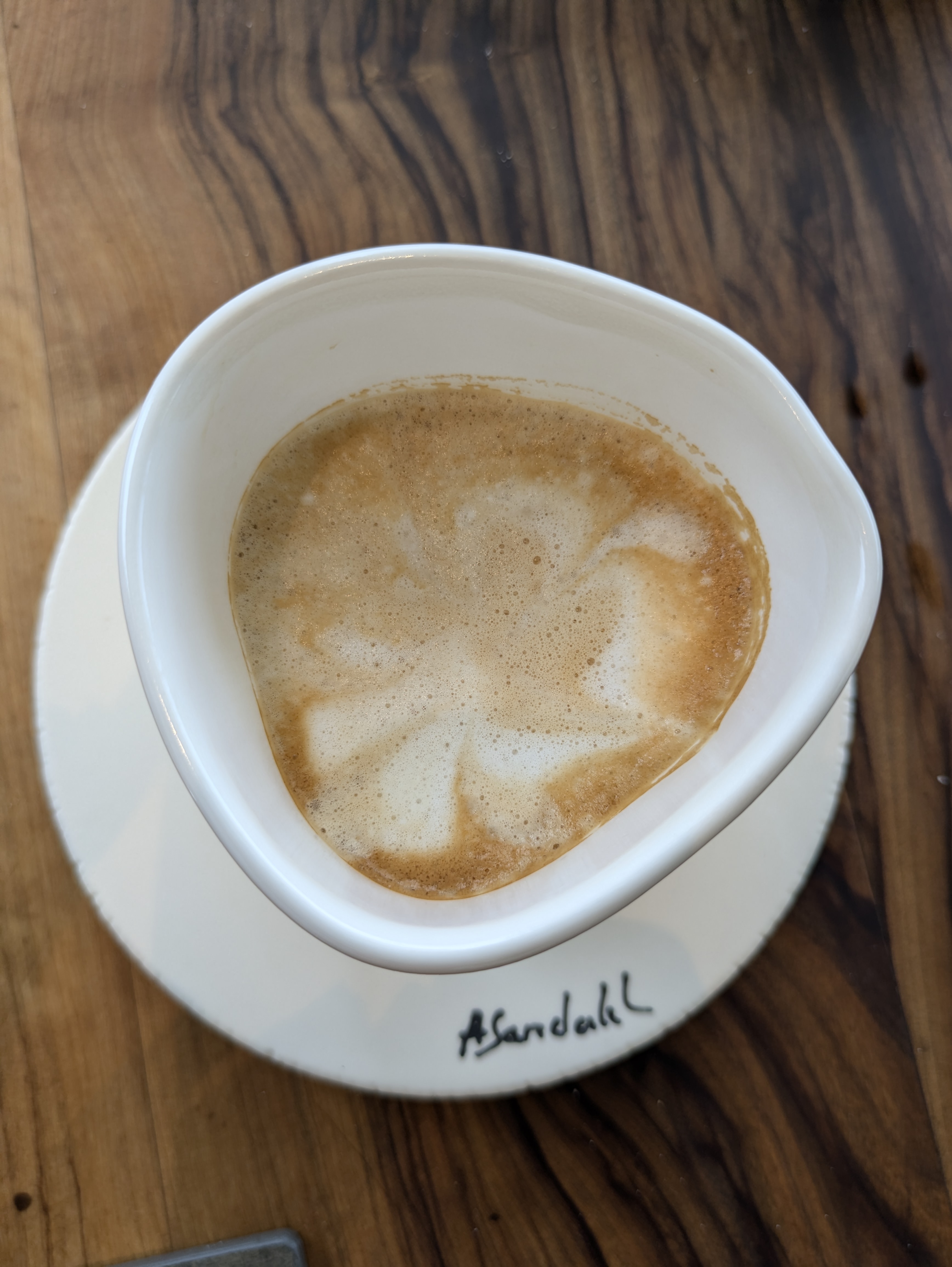 Cappuccino vu du dessus dans une tasse artisanale blanche sur une table en bois brut