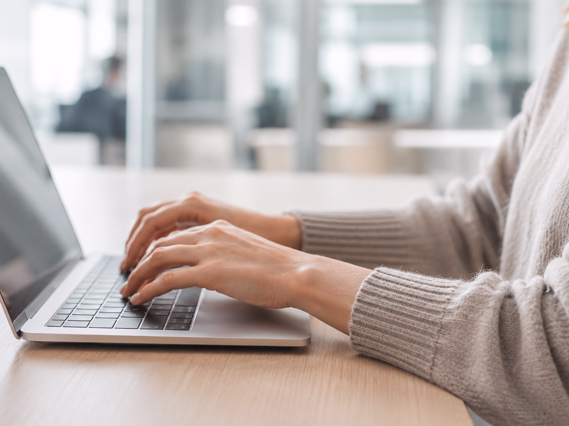 Hands typing on a laptop keyboard