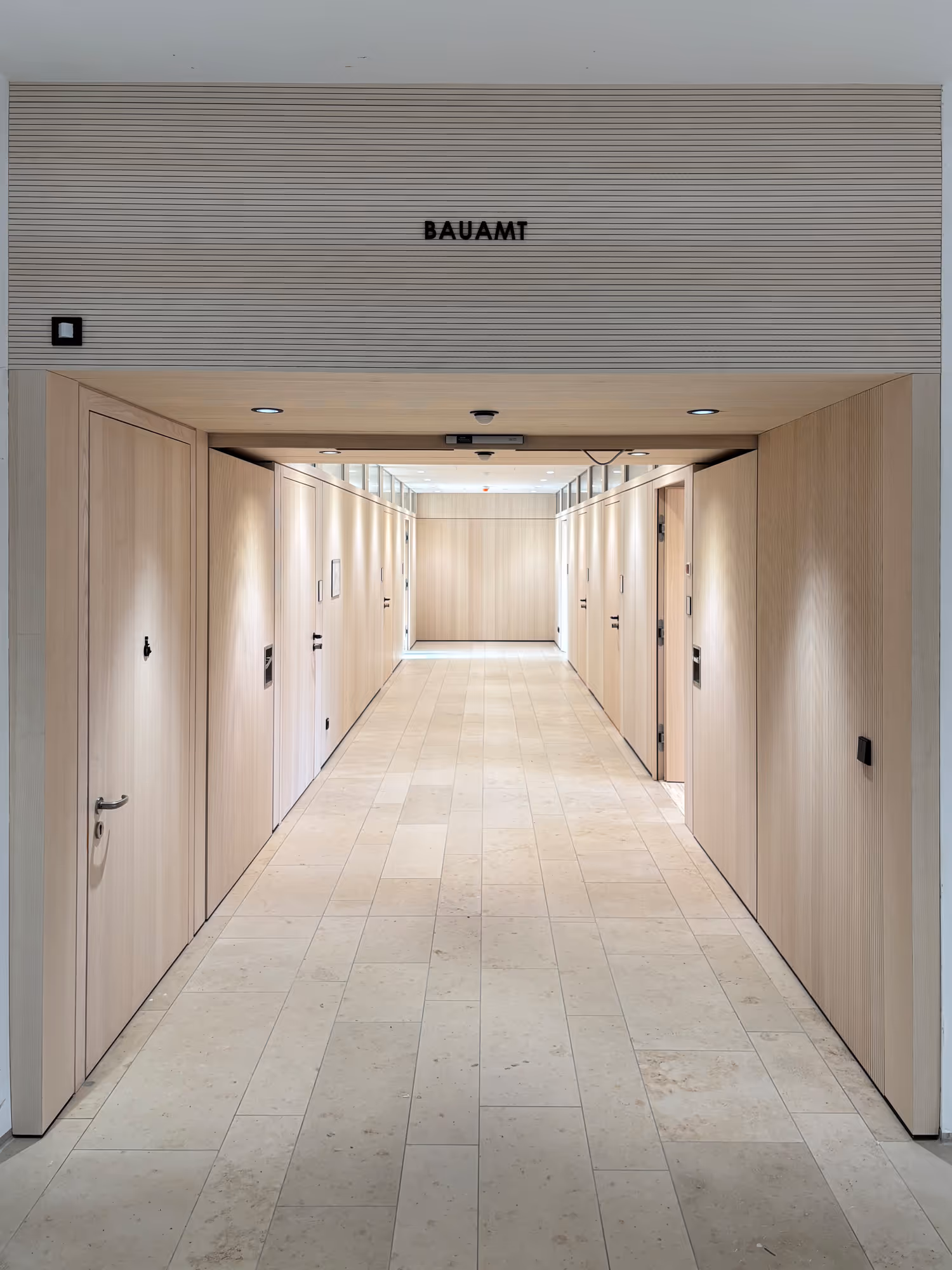 Heller Flur mit hellen Holztüren auf beiden Seiten und dem Schriftzug Bauamt über dem Eingang.