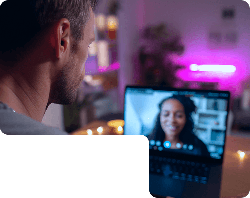 Person on video call with smiling woman in moody pink-lit home office