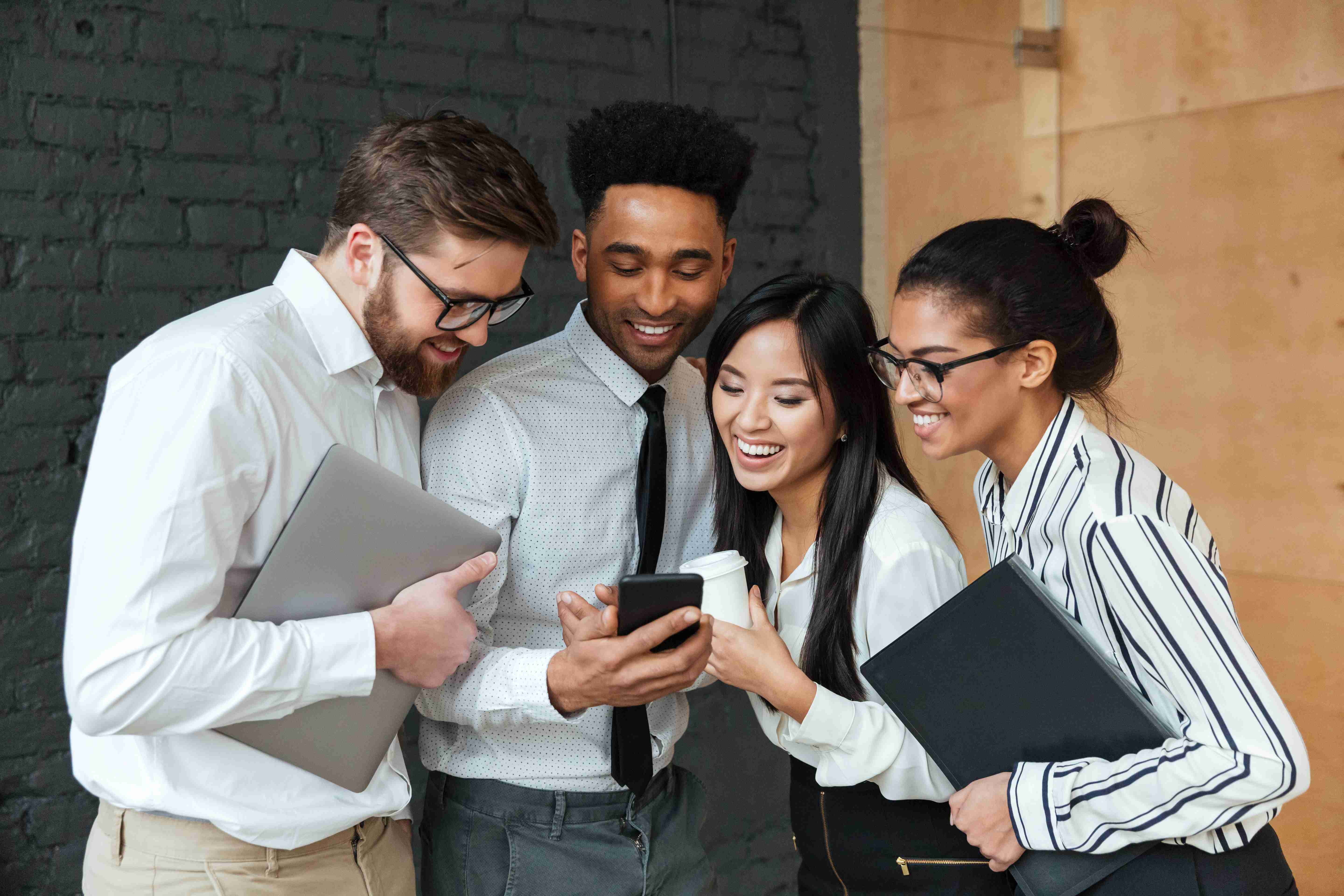 Diverse business team collaborating and smiling while looking at smartphone