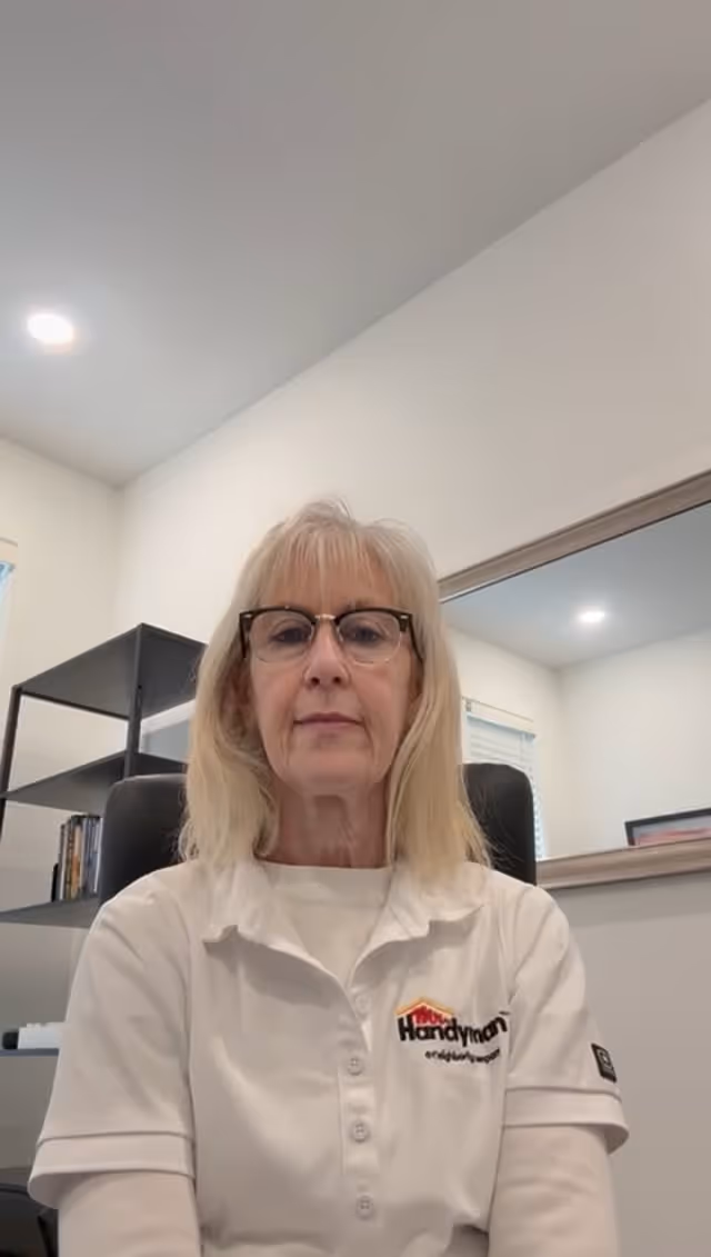 Woman in white Handyman shirt sits in office with bookshelves behind