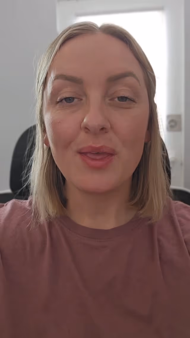 Person in pink shirt making a playful facial expression near window