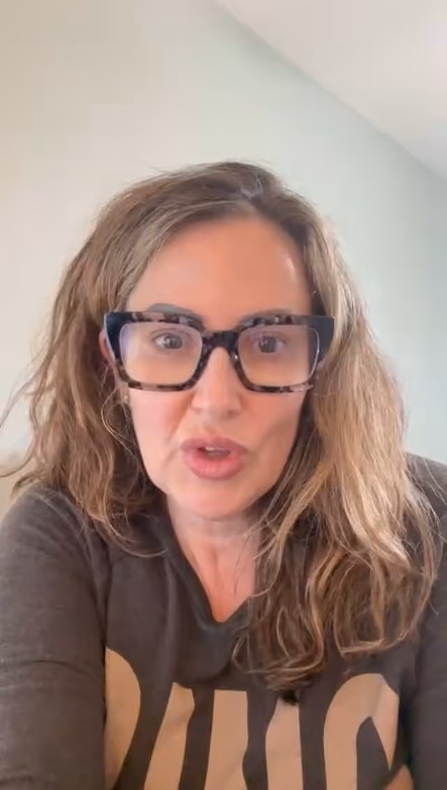 Person with glasses making an expressive face wearing a dark shirt