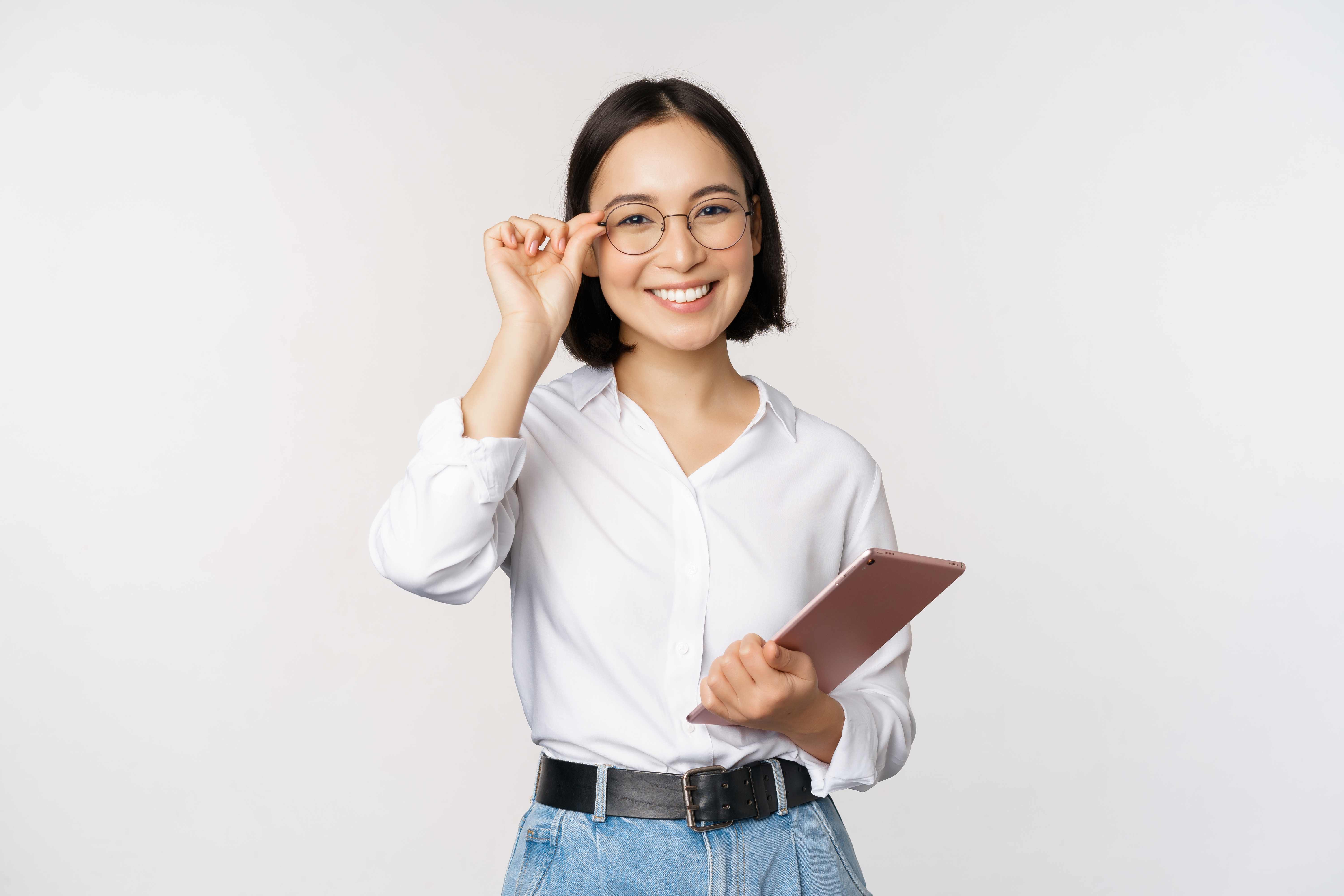 Smiling professional woman with glasses holding tablet, adjusting eyewear