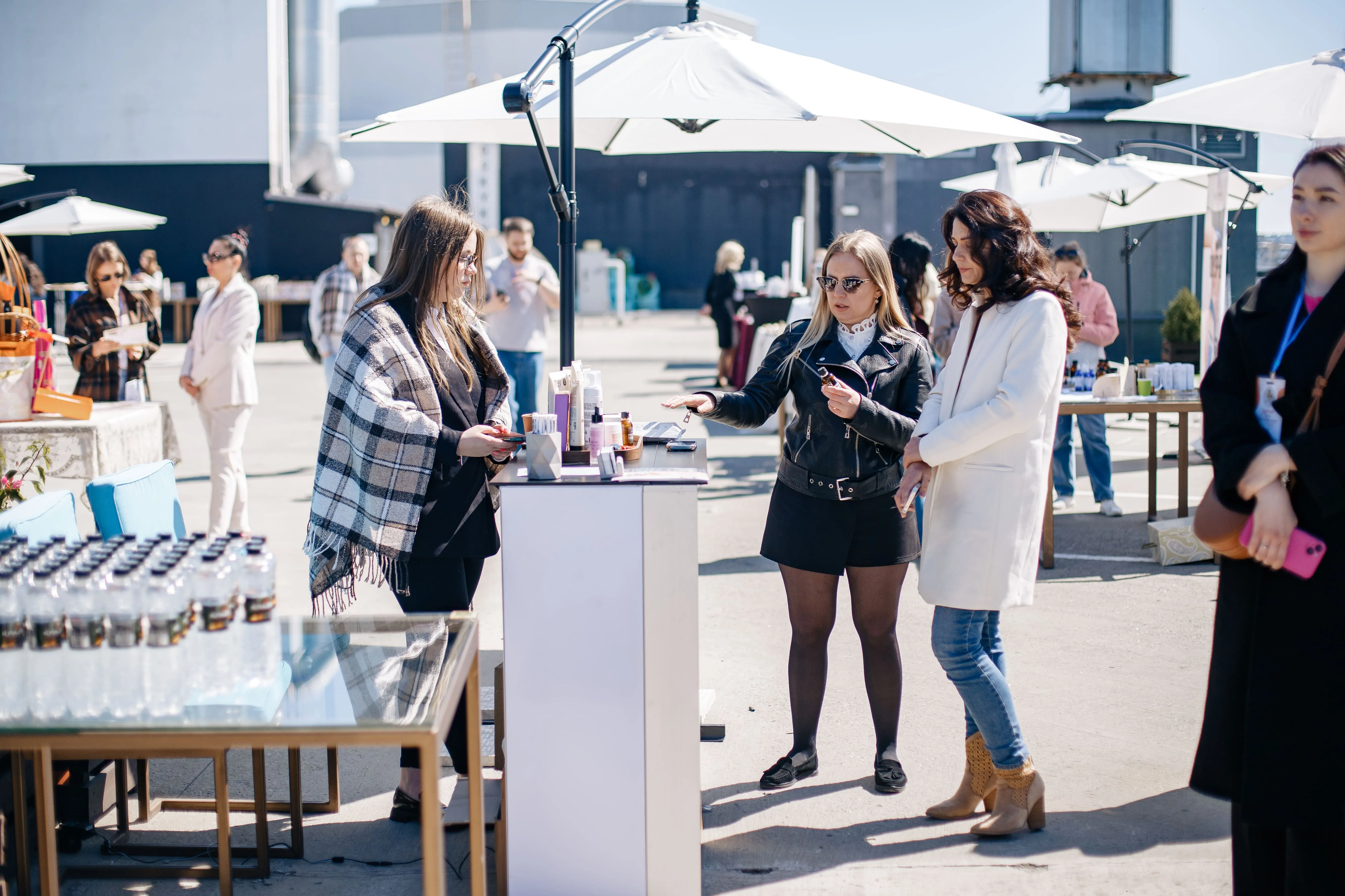 Учасниці заходу розглядають продукцію на виставковому столику під відкритим небом.