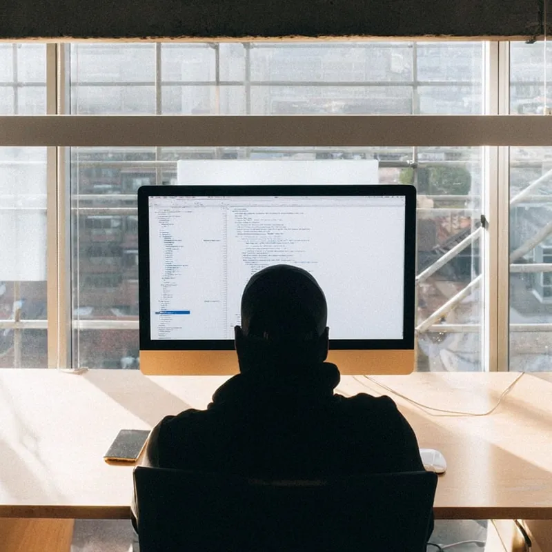 Modern developer workspace with a person sitting in front of monitors displaying code