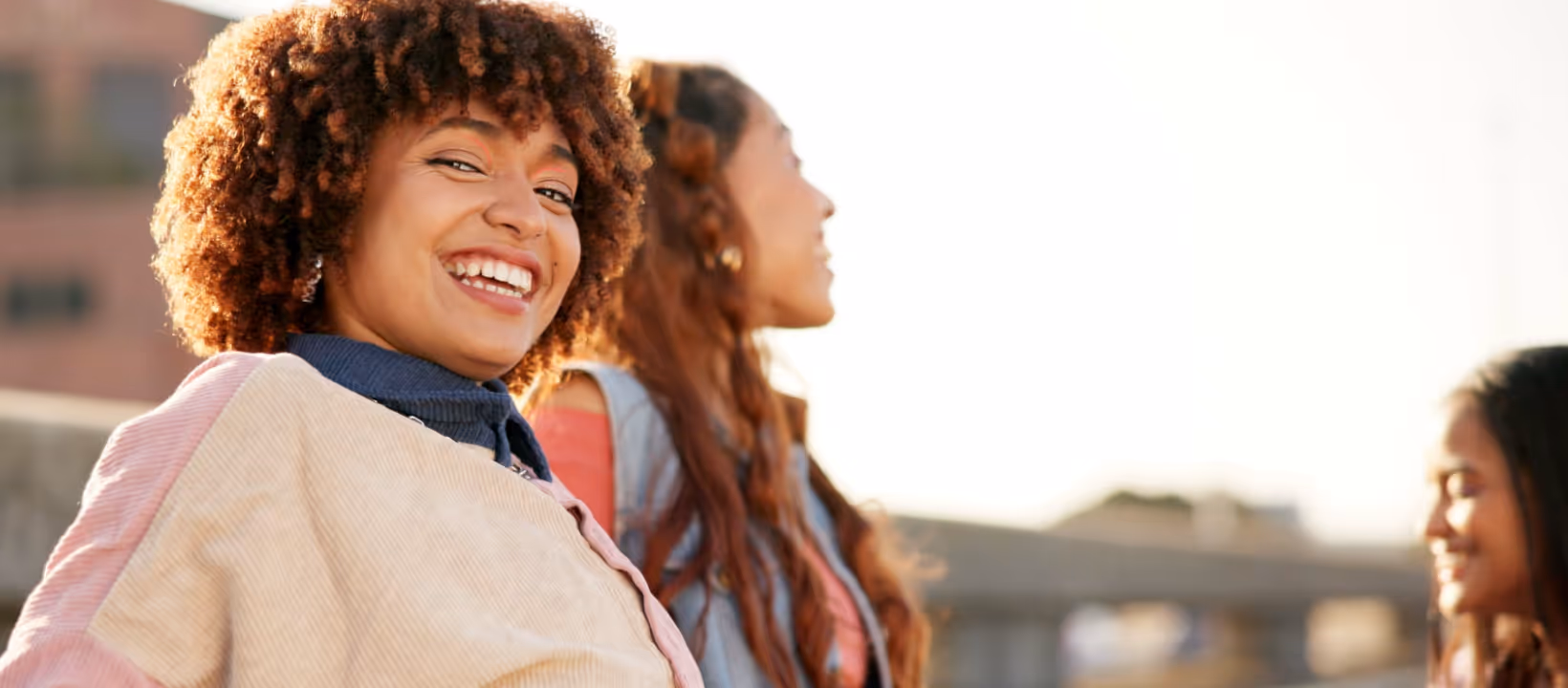 Two happy young women taking a cheerful selfie outdoors, smiling and laughing together on a sunny day.