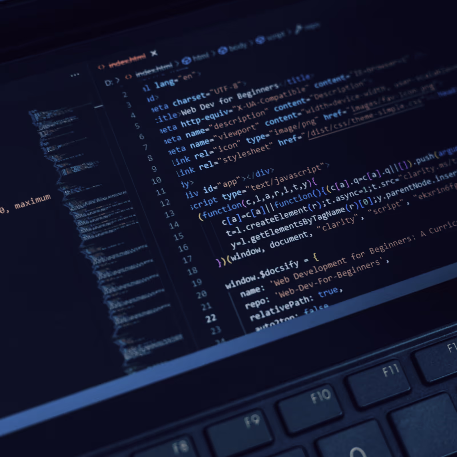 Close-up of a laptop screen displaying HTML and JavaScript code in a dark-themed text editor with part of a keyboard visible.